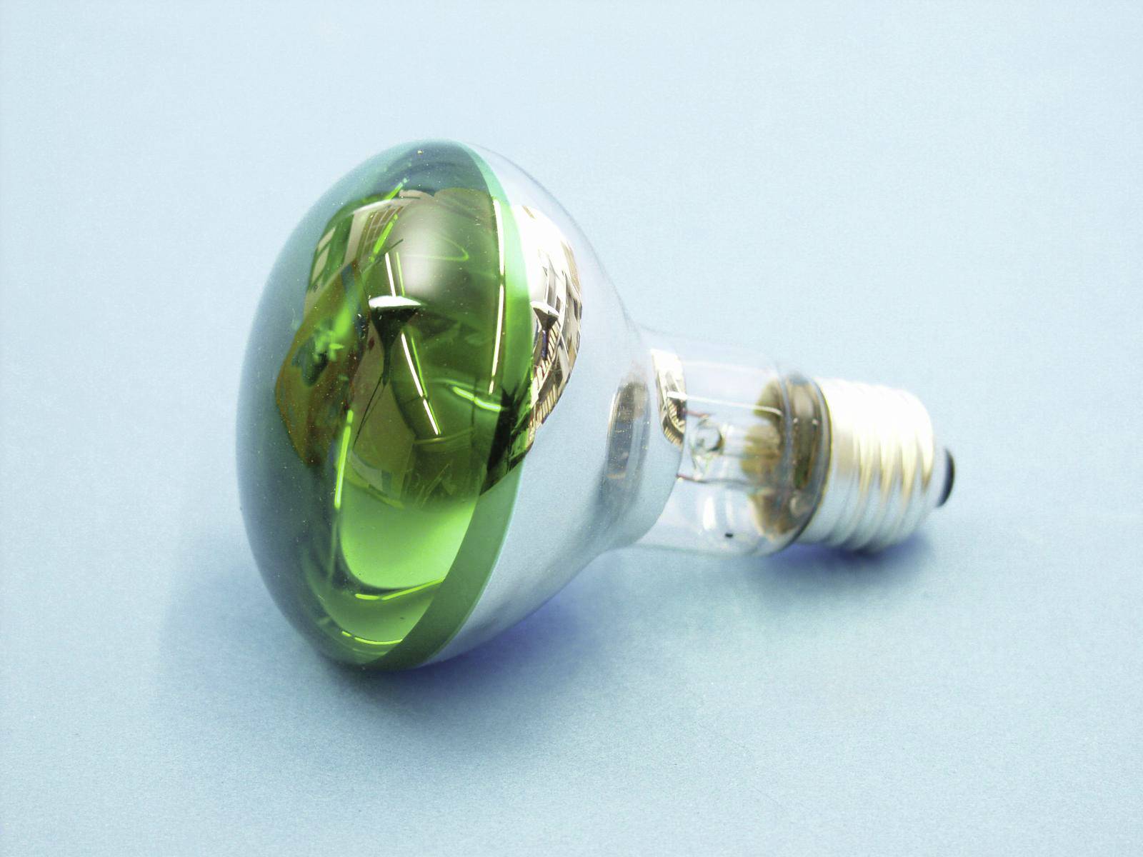 A light bulb with a green, reflective top is resting on a light blue background.