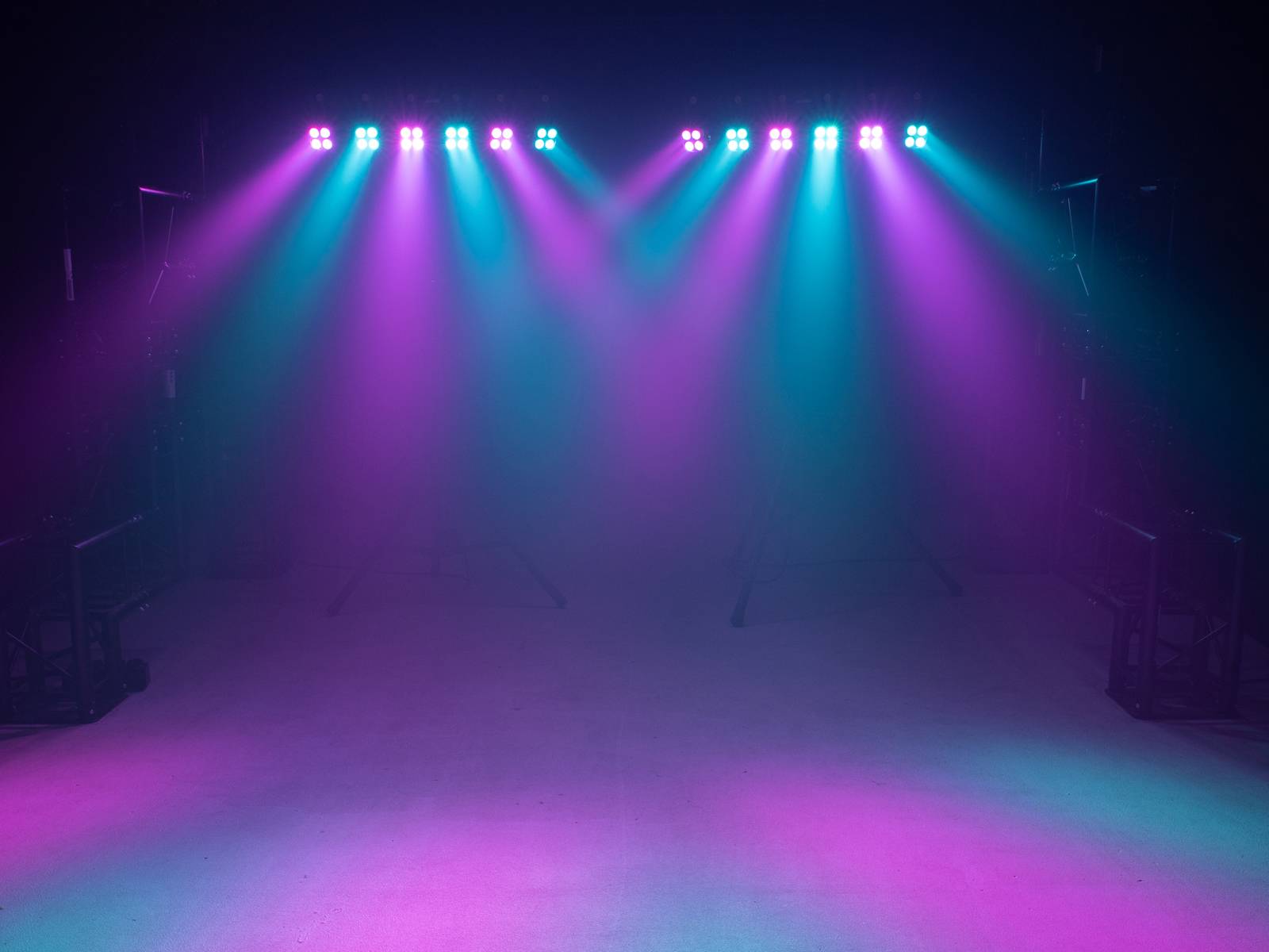 Stage lighting with pink and blue spotlights shining downwards. The colours blend softly on the stage floor.