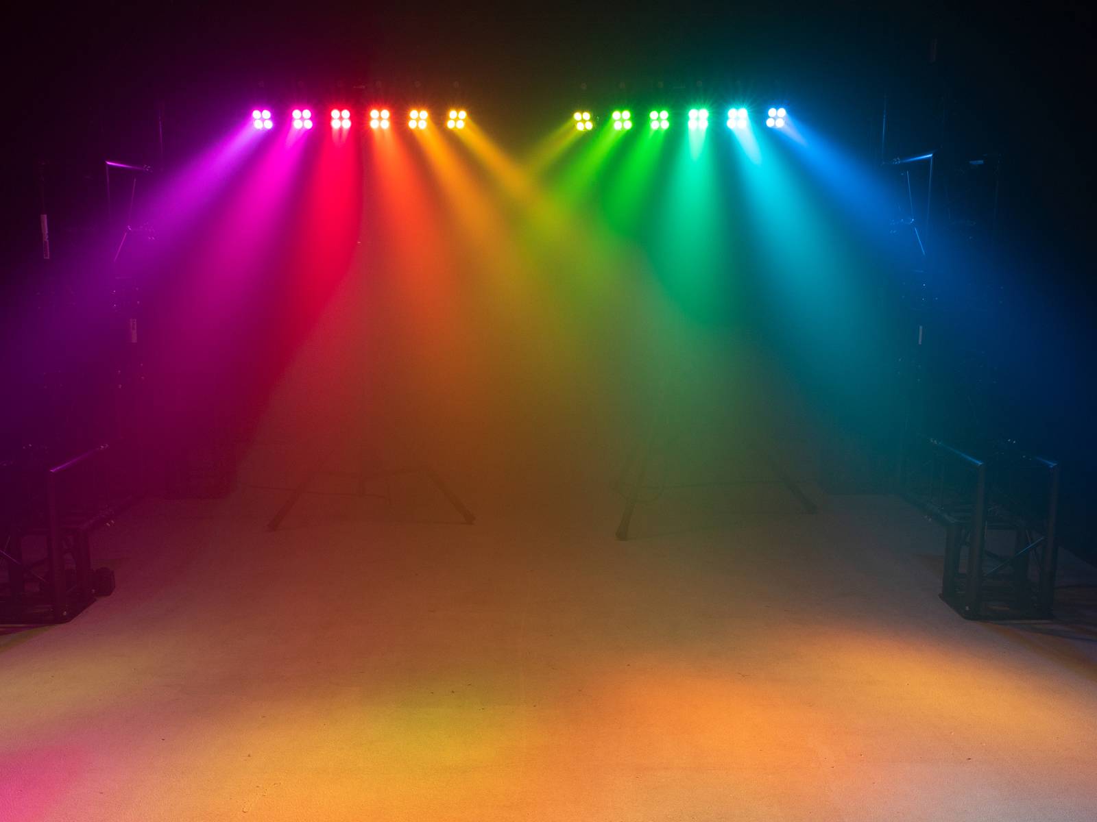 Colourful lights beam in a dark room in rainbow colours: Red, Orange, Yellow, Green, Blue, Purple. Atmospheric lighting.