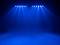 Several blue lights shine brightly and illuminate a dark stage from above. The atmosphere feels dramatic and focused.