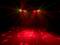 A dark stage illuminated by red spotlights and lasers radiating in different directions.