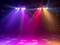 Colourful spotlights shine in blue, purple, red and yellow onto an empty stage, creating a vibrant, atmospheric ambience.