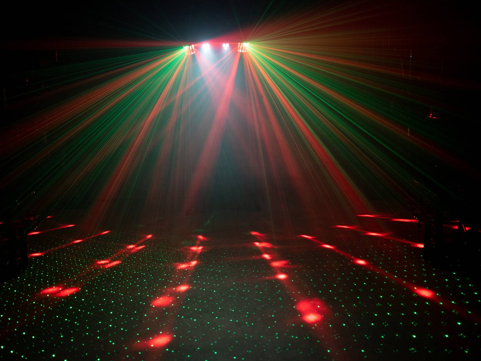 A dark disco with colourful laser lights projecting green and red beams across the dance floor.