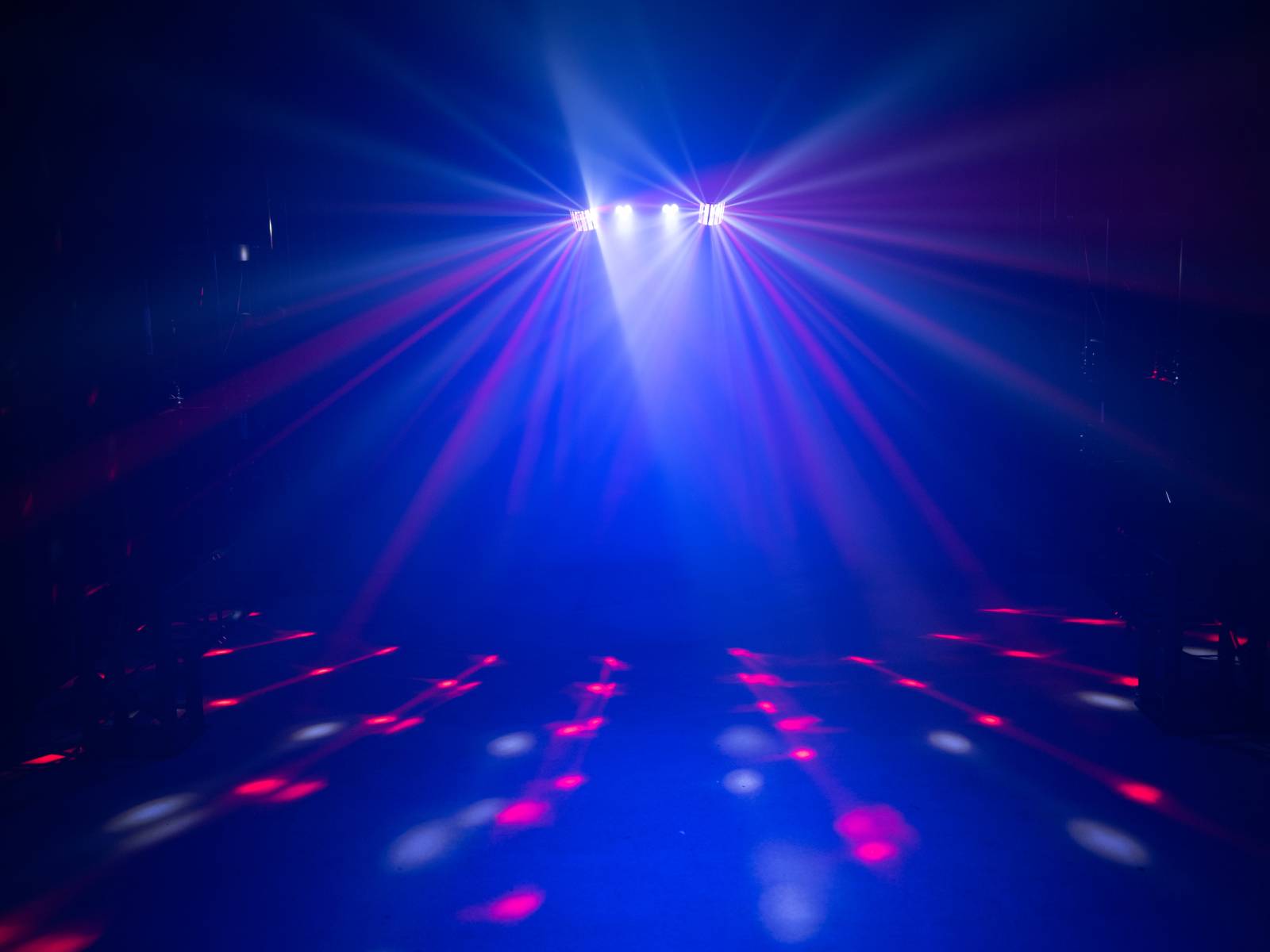 Colourful lights shine in a dark room, creating a dynamic pattern on the floor that generates a vibrant atmosphere.