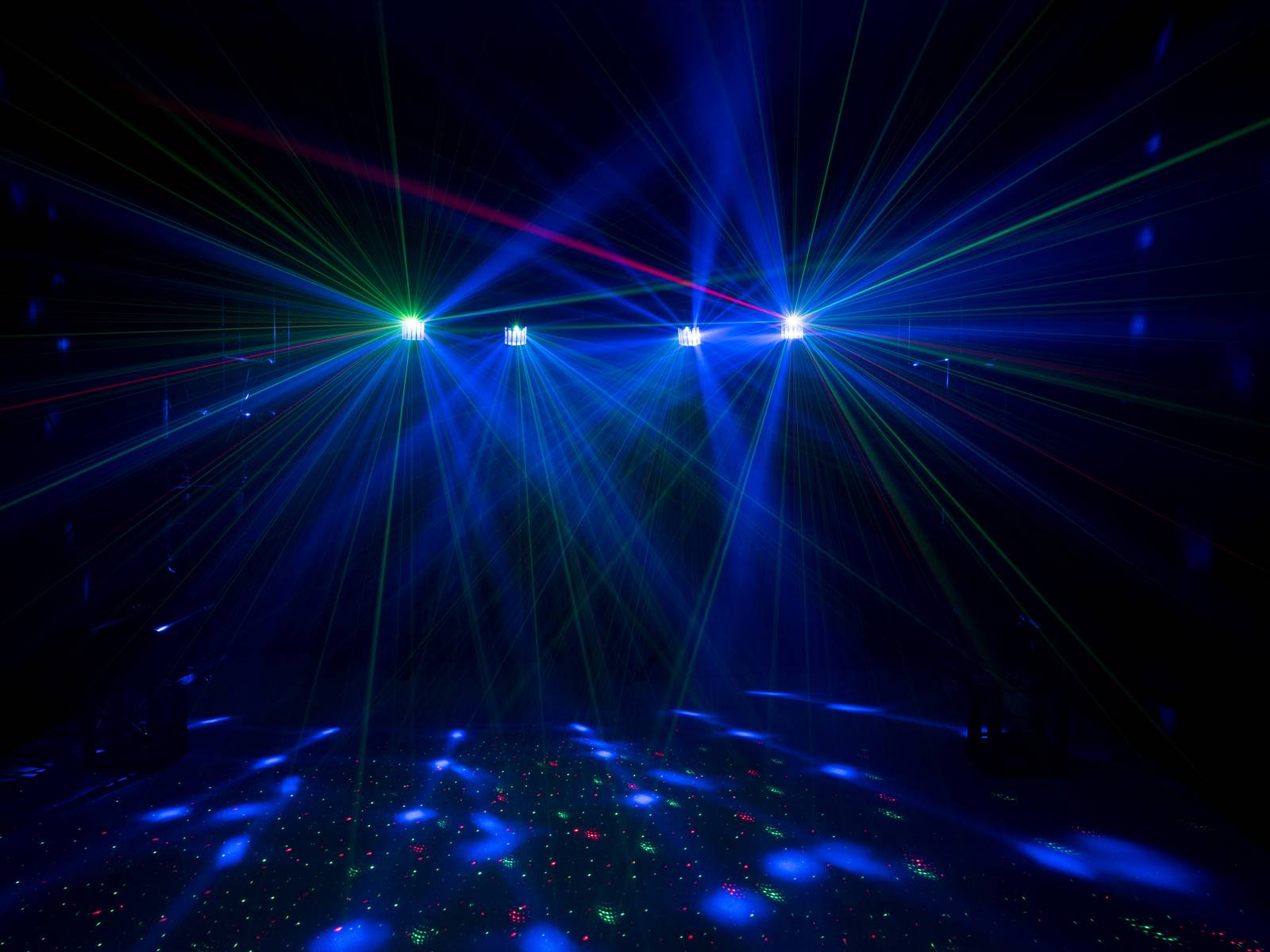 Multicoloured laser show with green, red and blue beams in a dark room. Beams intersect and create a vibrant pattern.