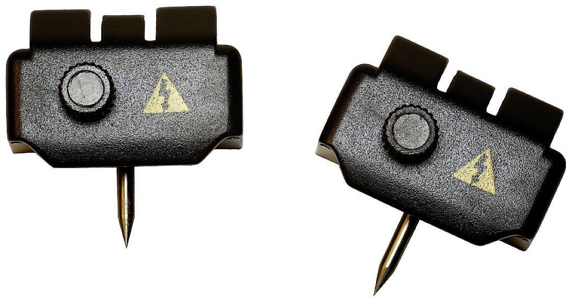 Two black, rectangular electrical test clips with a yellow warning symbol and metal pins for testing electrical contacts.