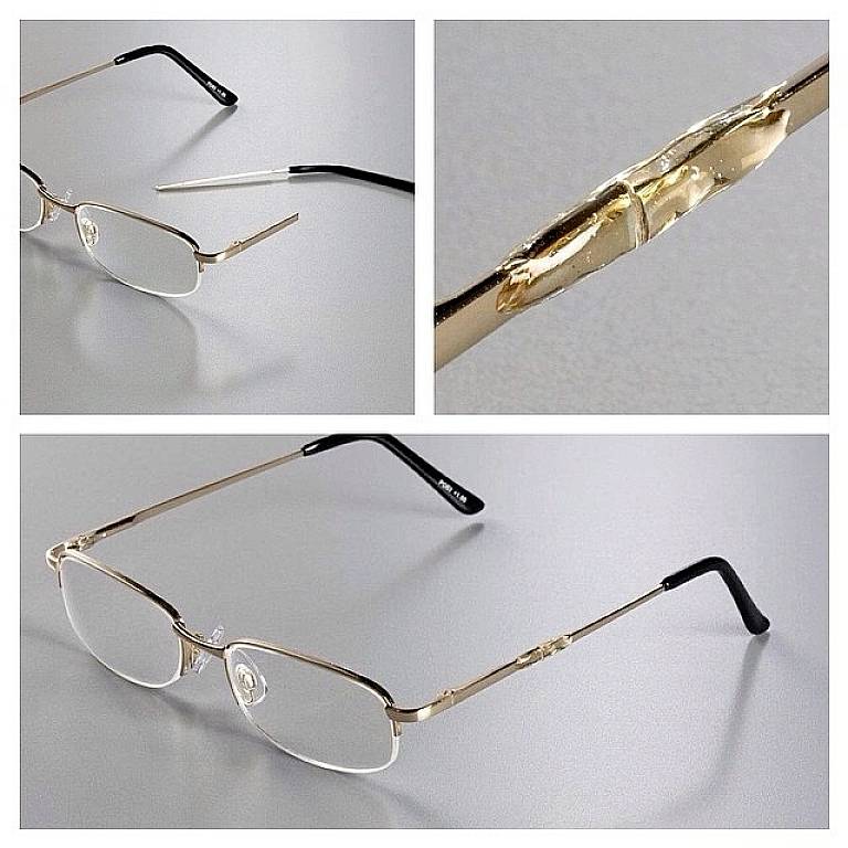 A broken pair of glasses with a fractured frame and detached arm, close-up showing the damage to the hinge and the entire glasses.