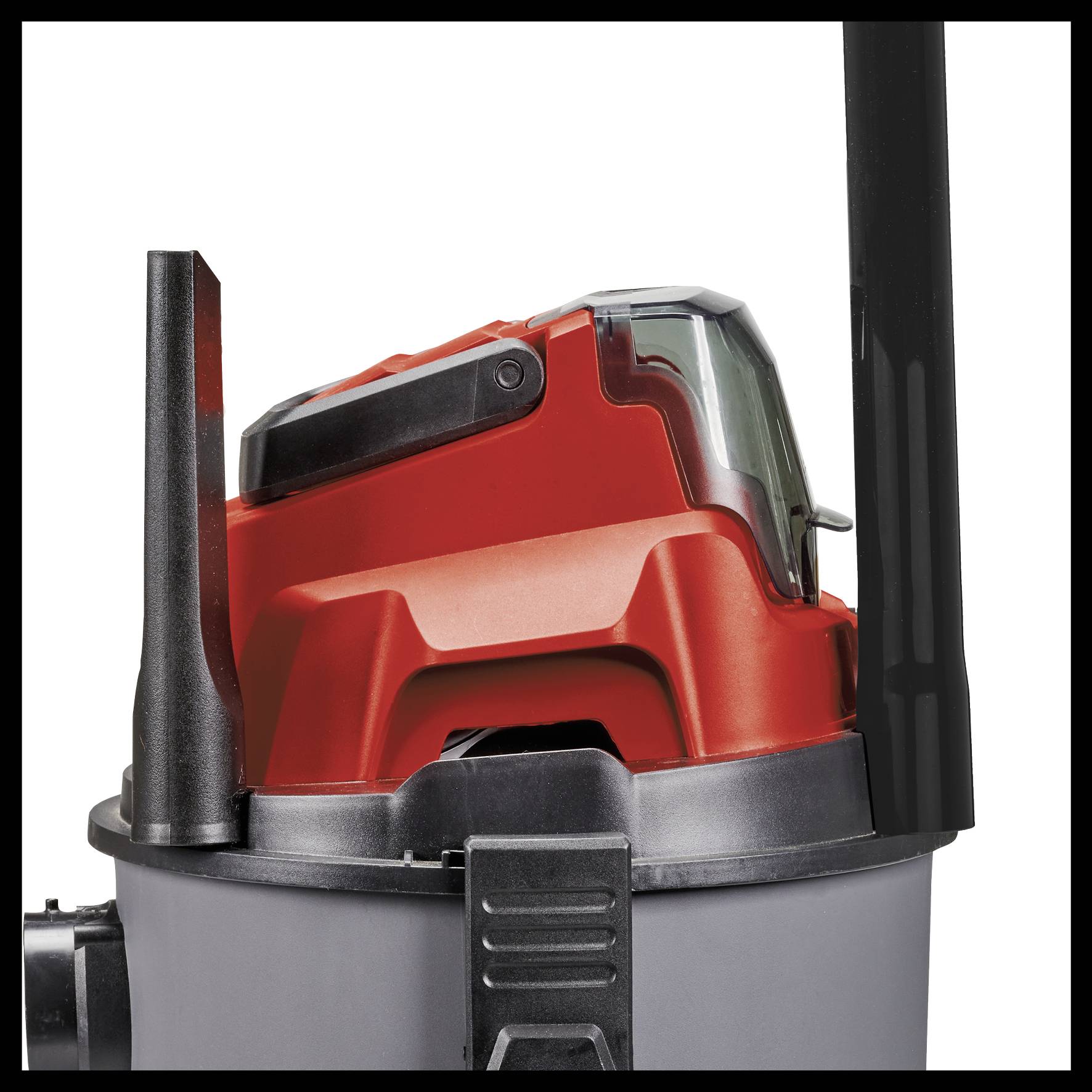 Industrial vacuum cleaner with a red casing and black handle. The device is partially visible and sits on a grey container.