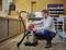 A man in a jumper checks an industrial vacuum cleaner in a workshop environment. Tool-laden shelves are visible in the background.