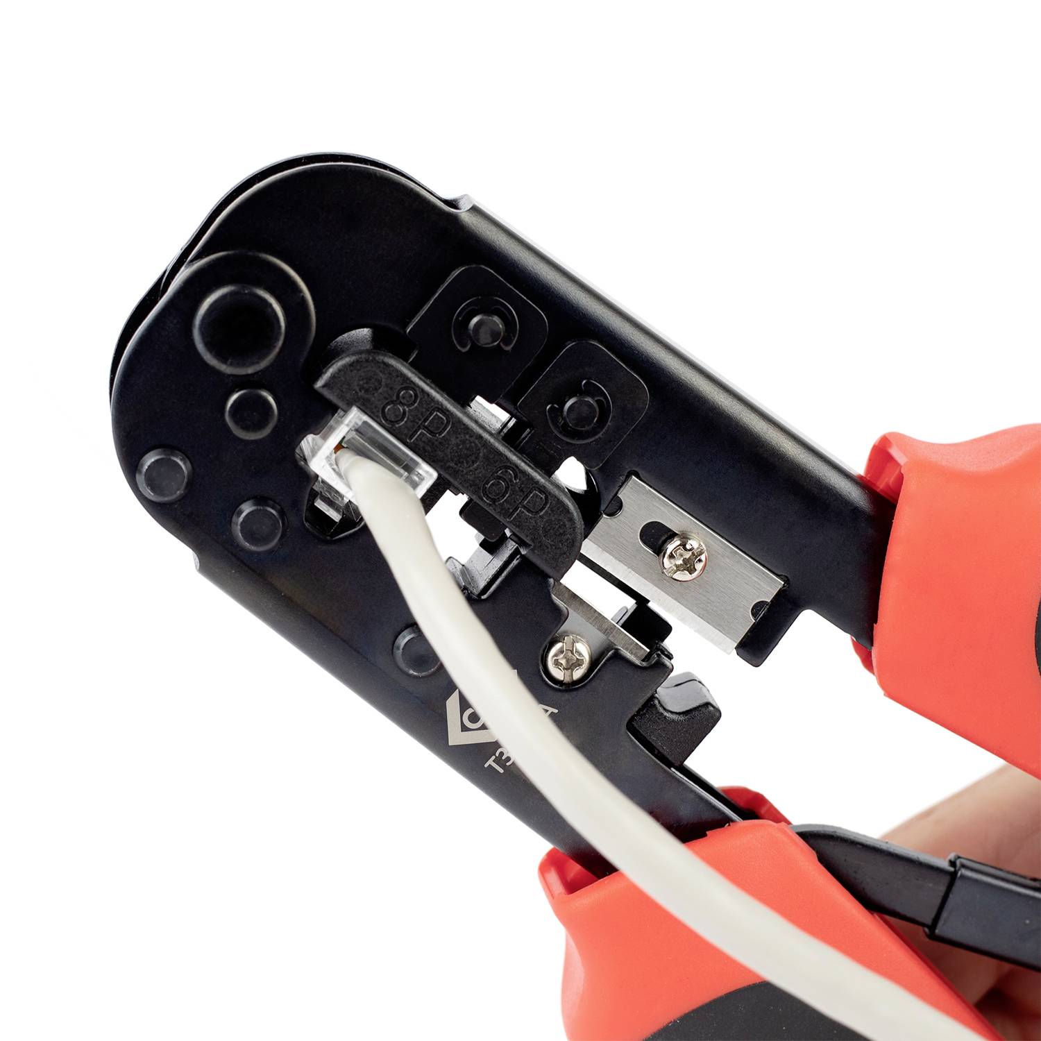 A hand is using a crimping tool to secure a metal connector to a cable. The tool has black and red handles.