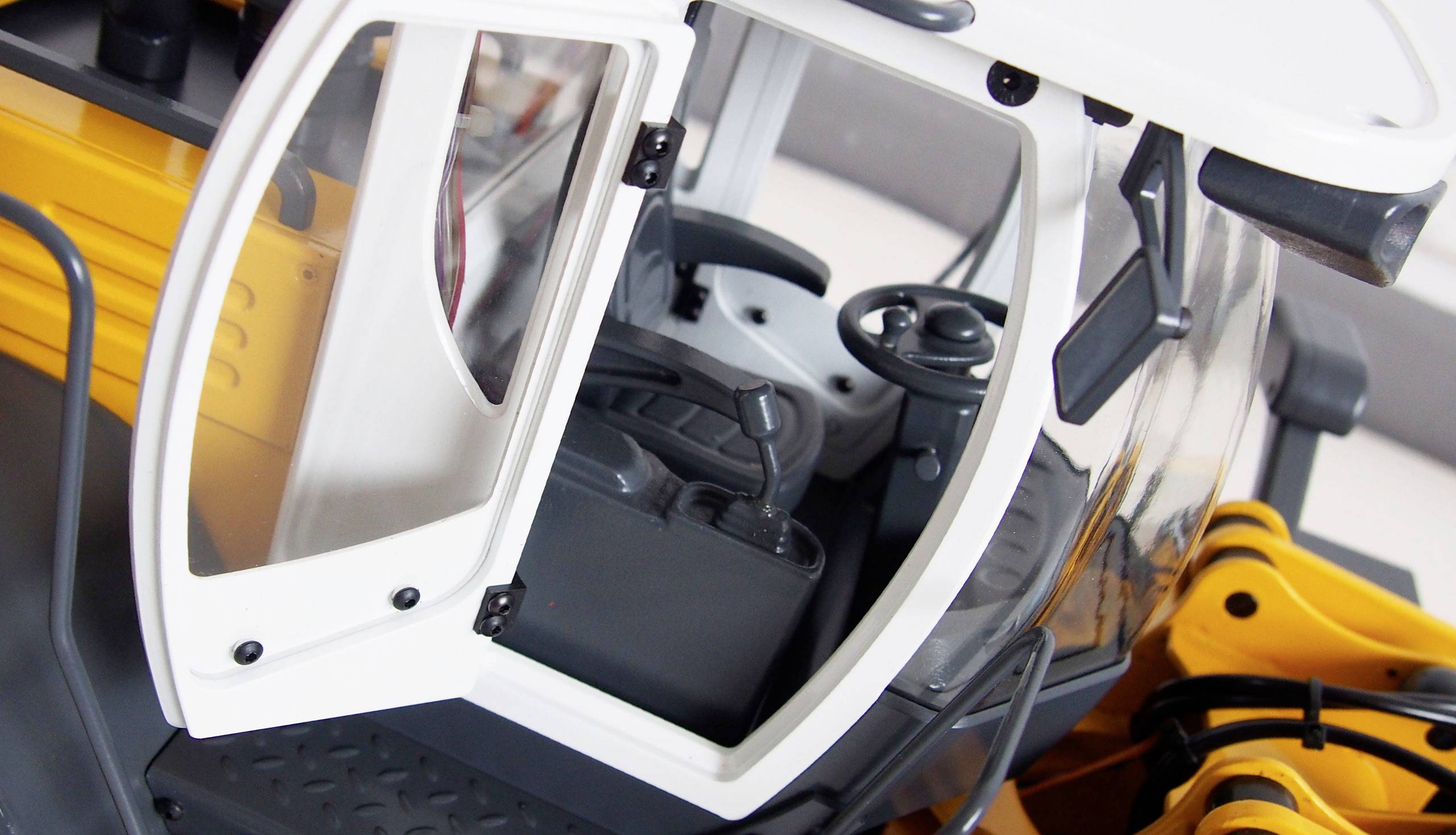 An open driver's cab of a yellow excavator with a visible steering wheel and seat.