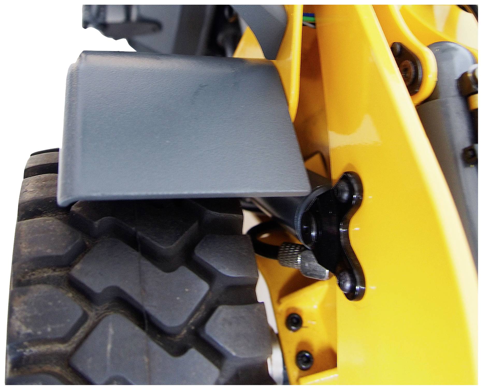 Close-up of part of a yellow machine with large rubber tyres and black handle.