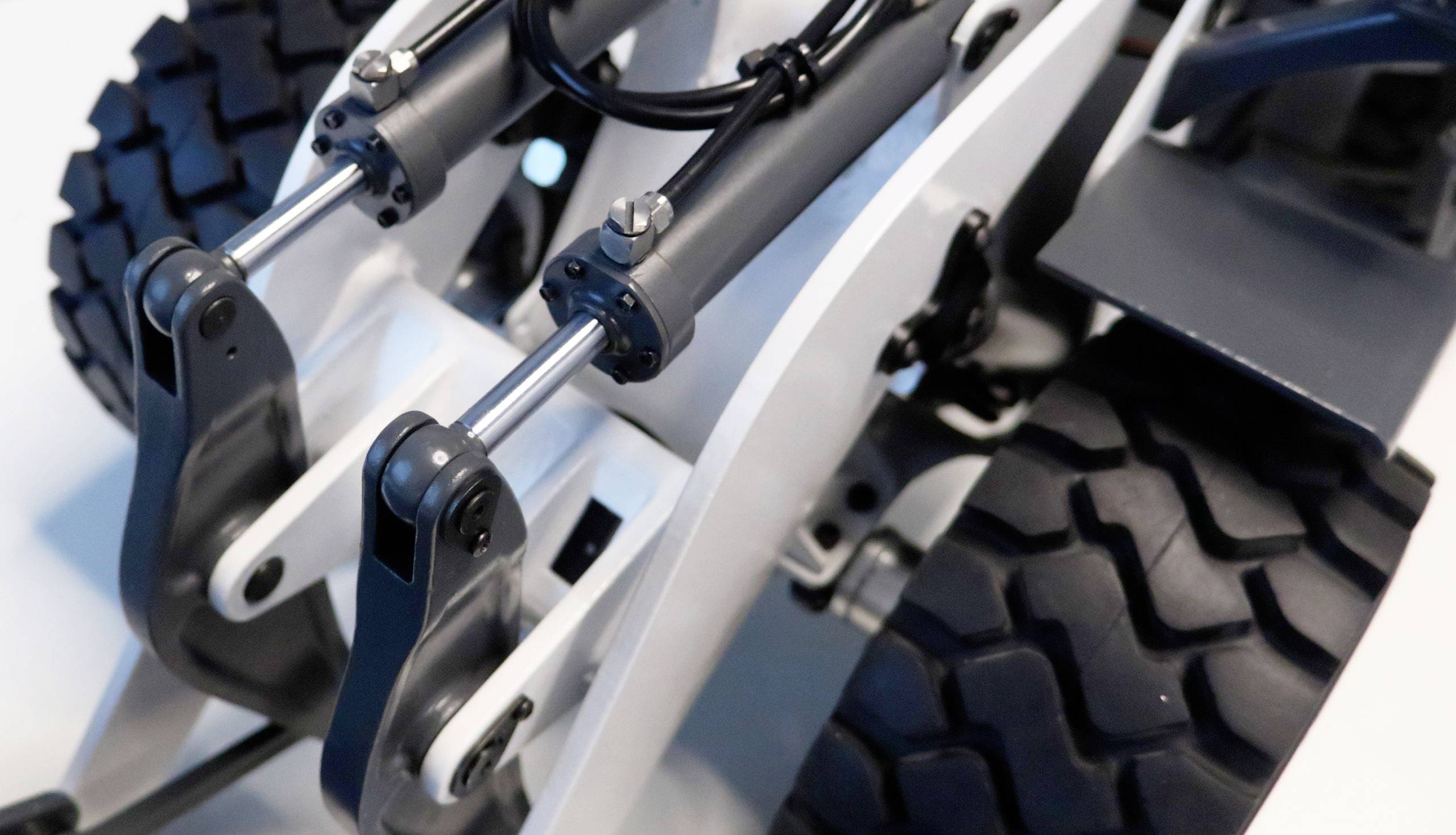 Close-up of a mechanical device with two large wheels and hydraulic arms designed for heavy lifting operations.