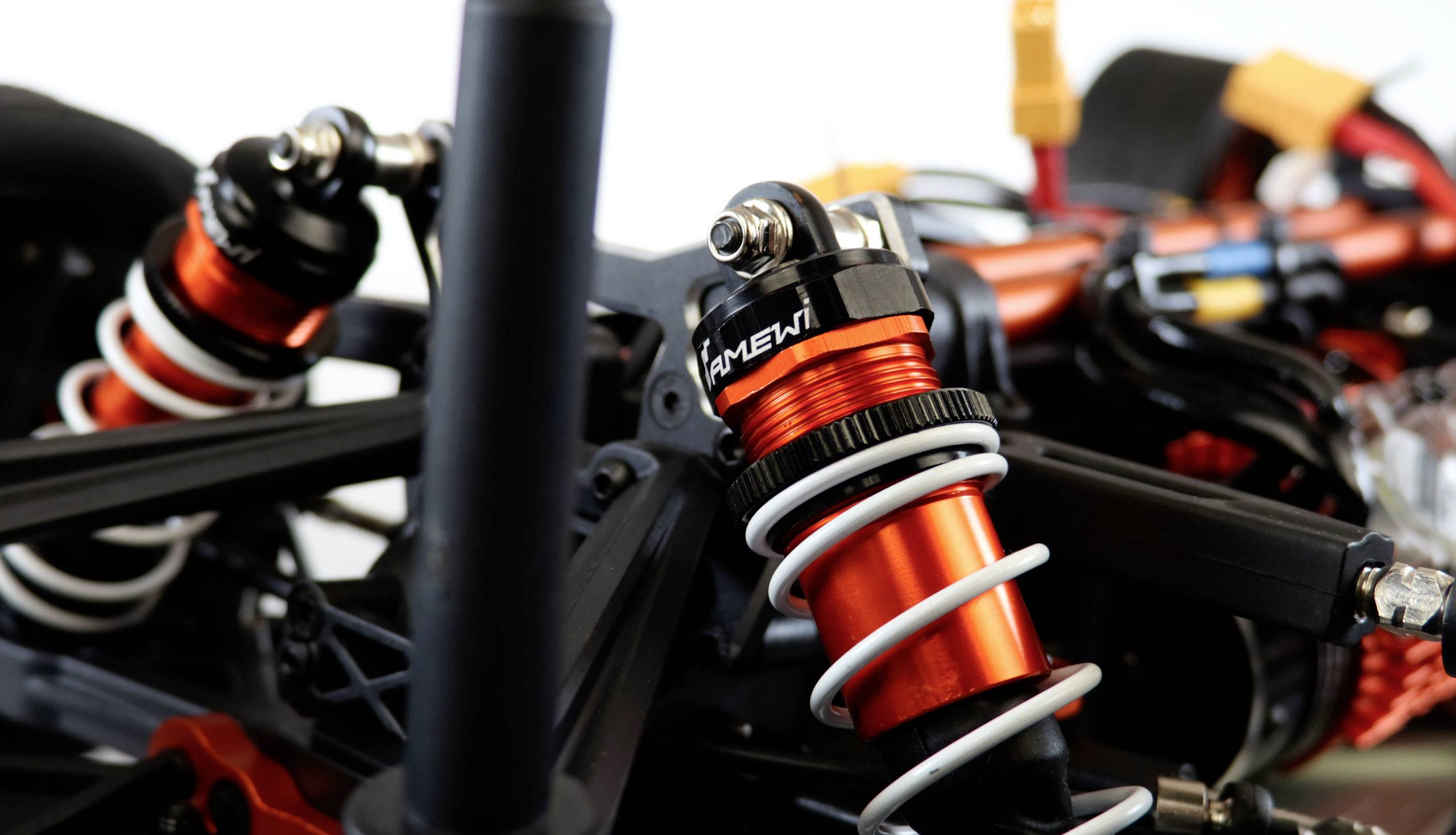 Close-up of a red shock absorber of a remote-controlled car, surrounded by black and red vehicle parts.