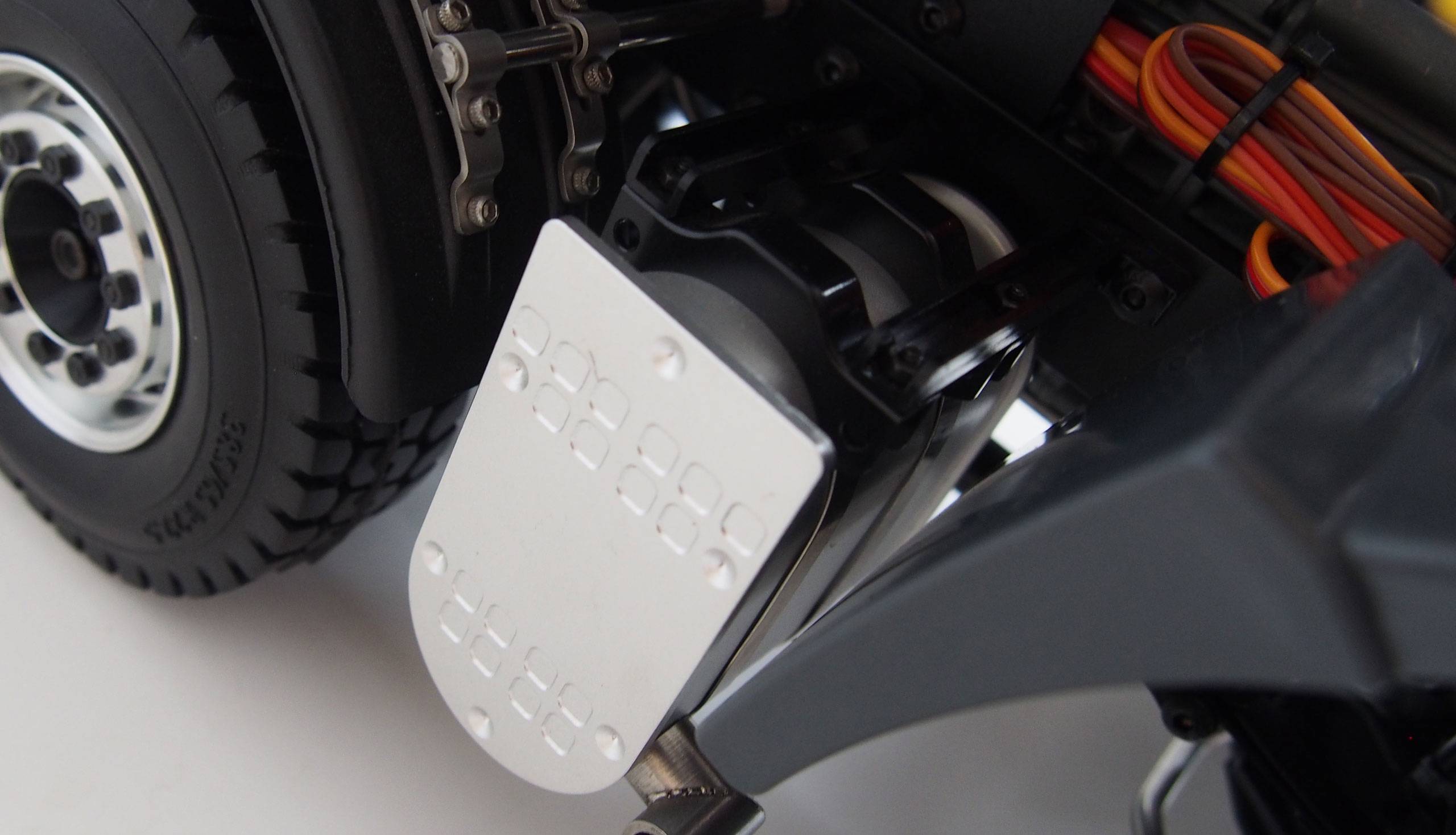 Close-up of a lorry model with a visible part of the wheel, metal mudguard and cables. Highly detailed technical imagery.