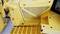 Close-up of a yellow construction machine with a non-slip tread surface and ventilation grille, showing details of construction and material structure.