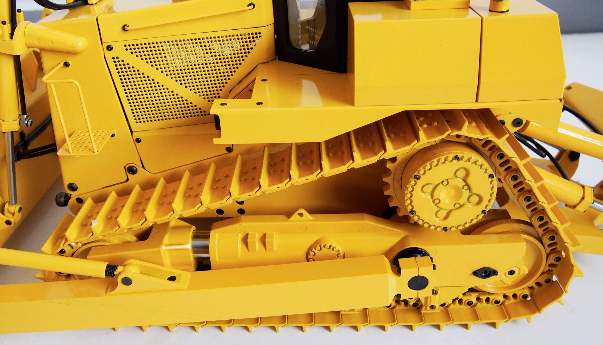 A yellow tracked excavator with detailed tracks and mechanics, focusing on the side view of the running tracks and gears.