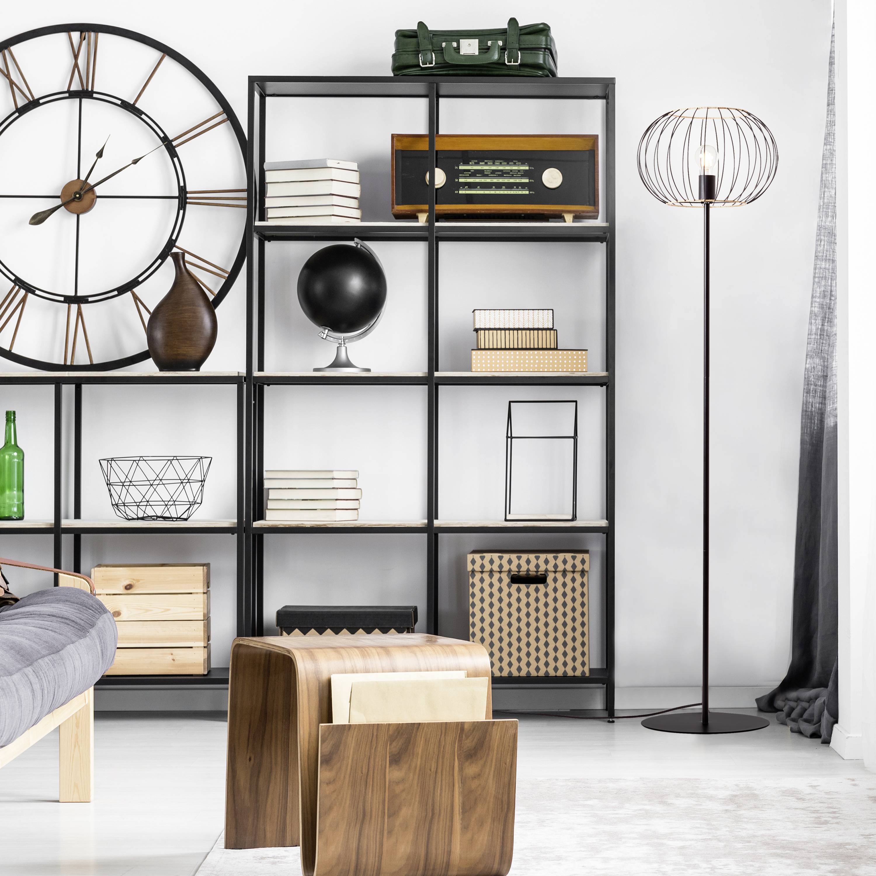 Living room with modern furniture: A bookshelf with books and decorations, a large wall clock, a floor lamp, and a sofa.