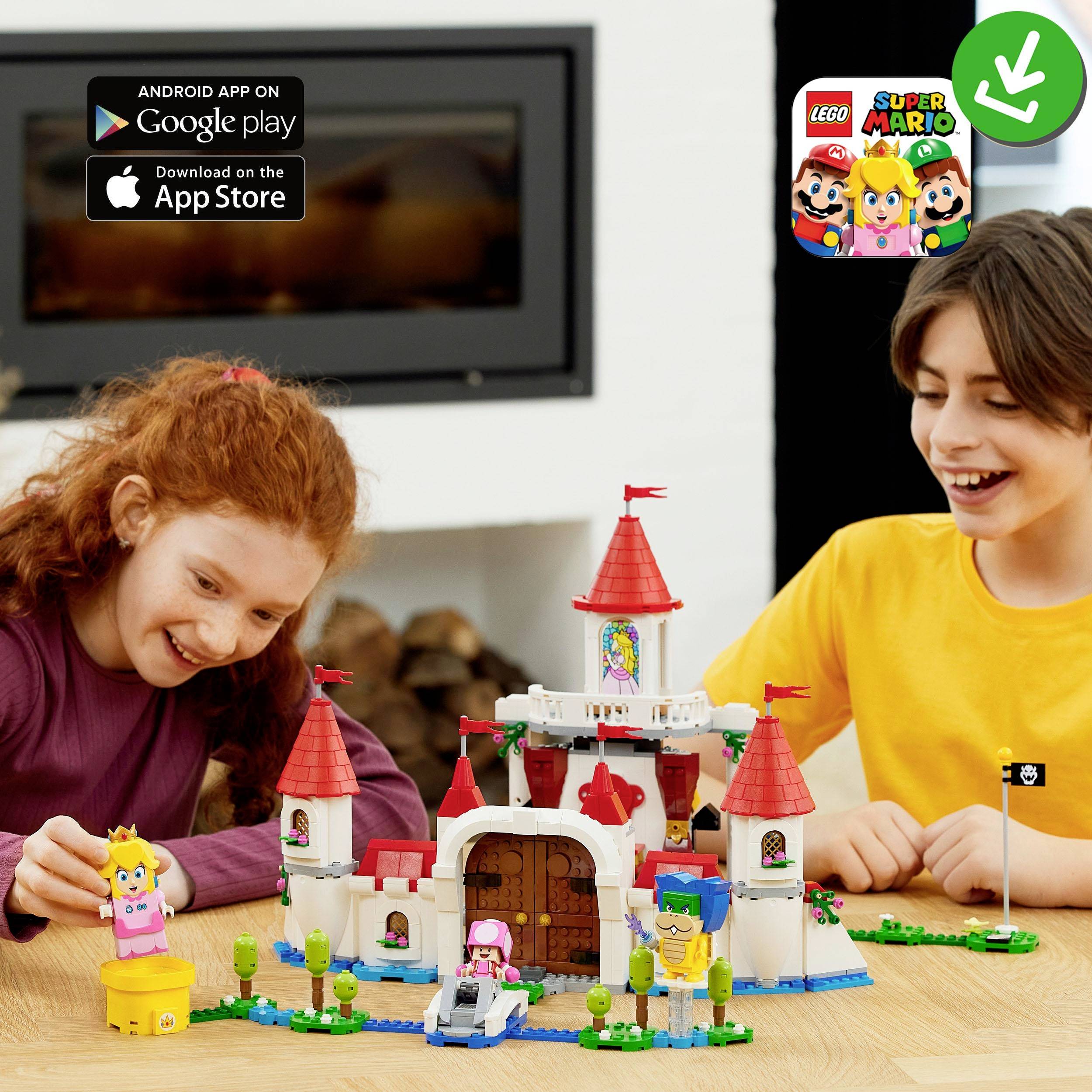 A boy and a girl are playing with a LEGO Super Mario Castle set. In the background, the logos for Google Play and the App Store are visible.