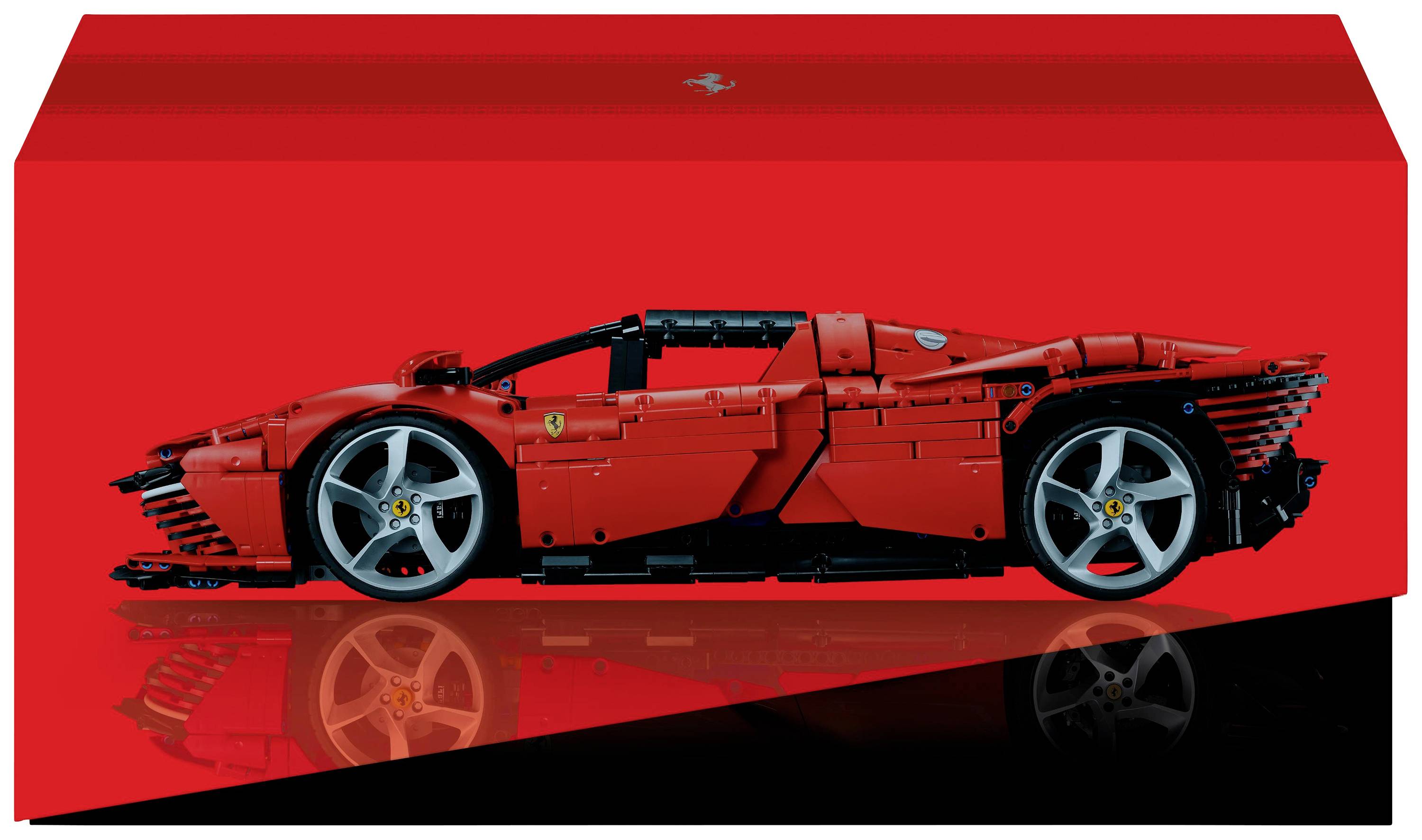 A red model of a sports car made from building blocks, viewed from the side, on a red and black background.