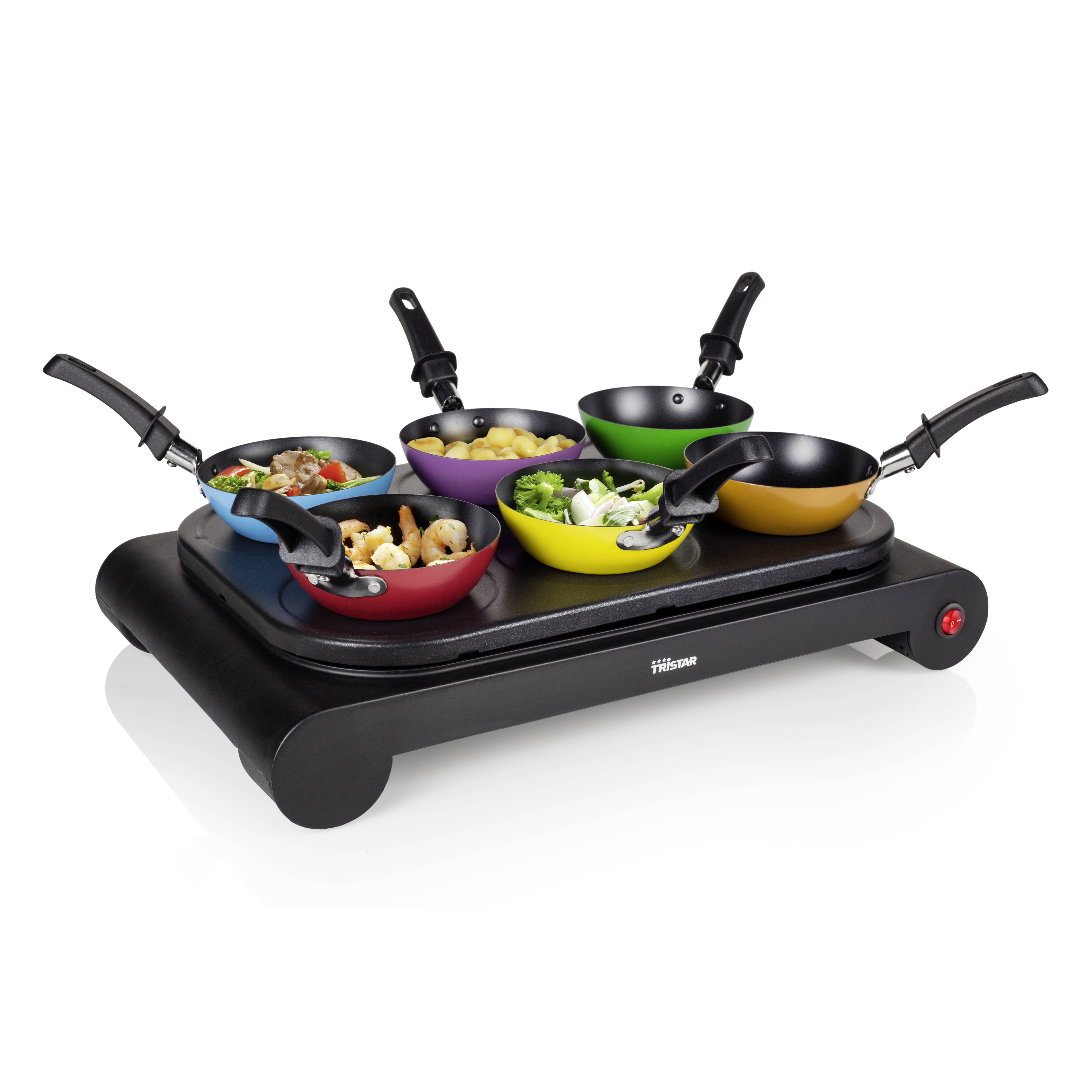 A raclette grill with six small, colourful pans, filled with various dishes, on a black heating plate.