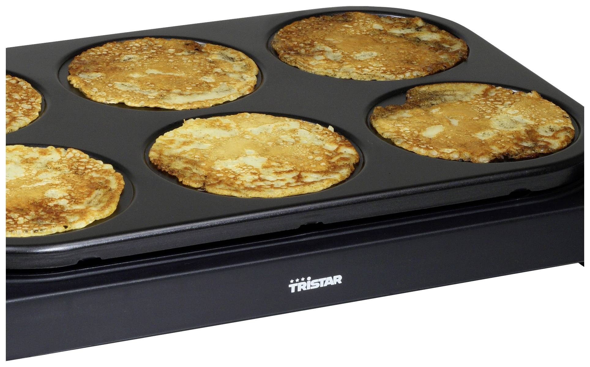A pan with six round moulds, each containing a golden-brown baked pancake, on a hob.