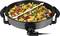 A round electric frying pan filled with colourful vegetables and meat. It has handles on the sides and a temperature control dial at the front.