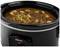 A black slow cooker by Tristar containing a stew with potatoes, pieces of meat, and bay leaves.