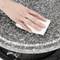 A hand wipes a granite surface clean with a white cloth.