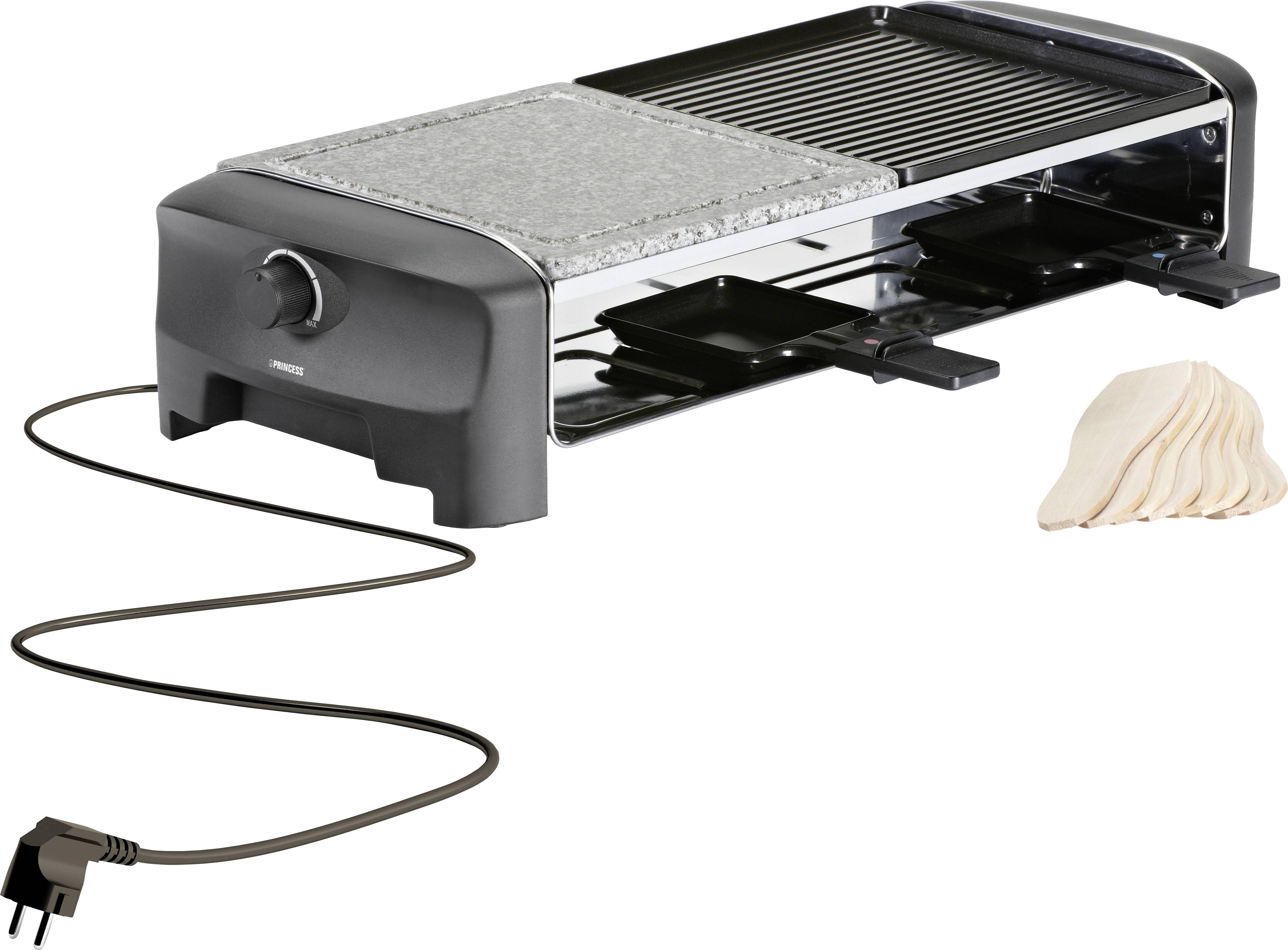 A raclette grill with two small pans and a natural stone plate. Beside it lies a small quantity of raclette cheese. The grill is plugged in.