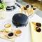 Waffle maker on kitchen worktop, surrounded by waffle cones and sauces. Basil in a vase, cooking pot on the hob in the background.