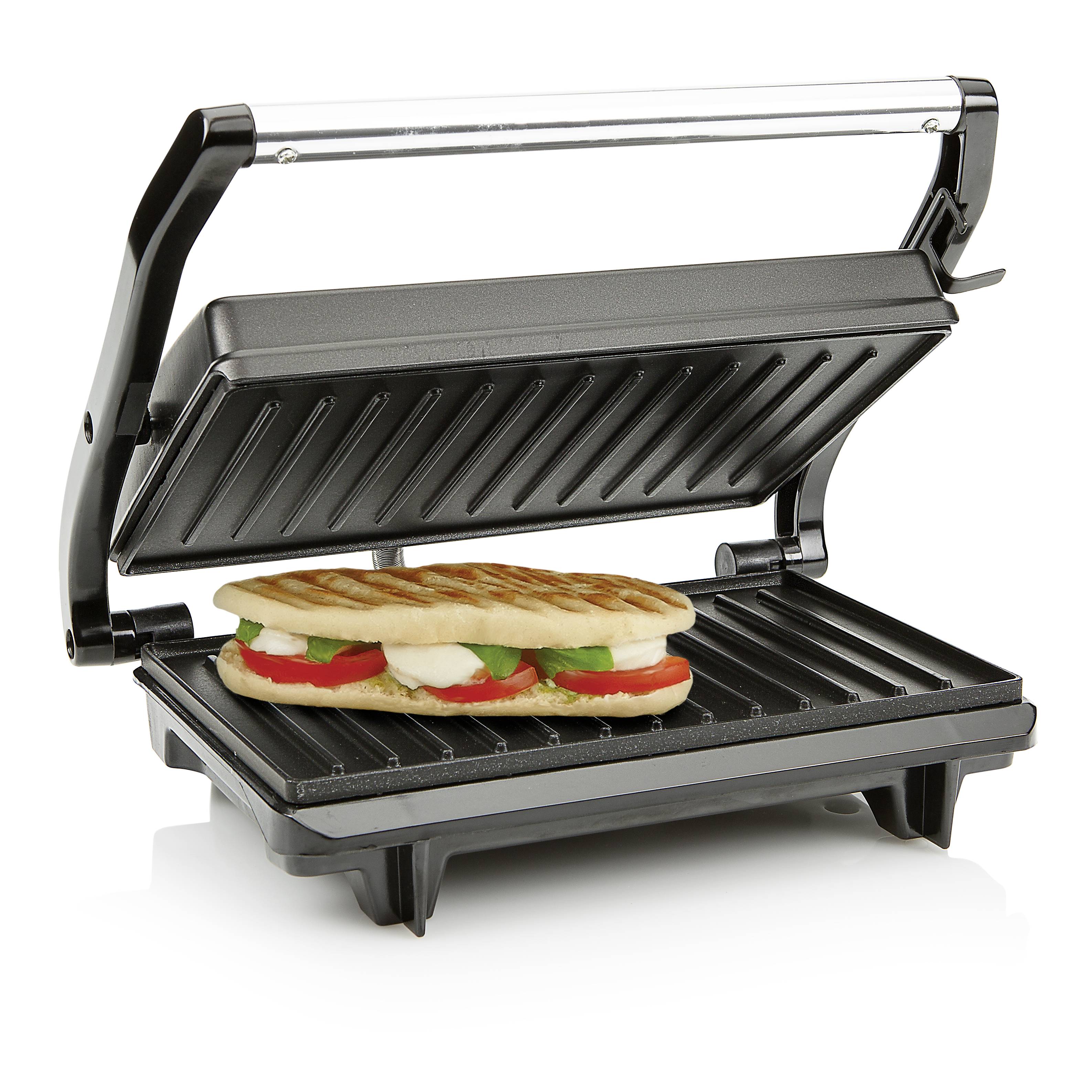 An open contact grill with a grilled panini inside, topped with tomatoes, mozzarella, and basil.