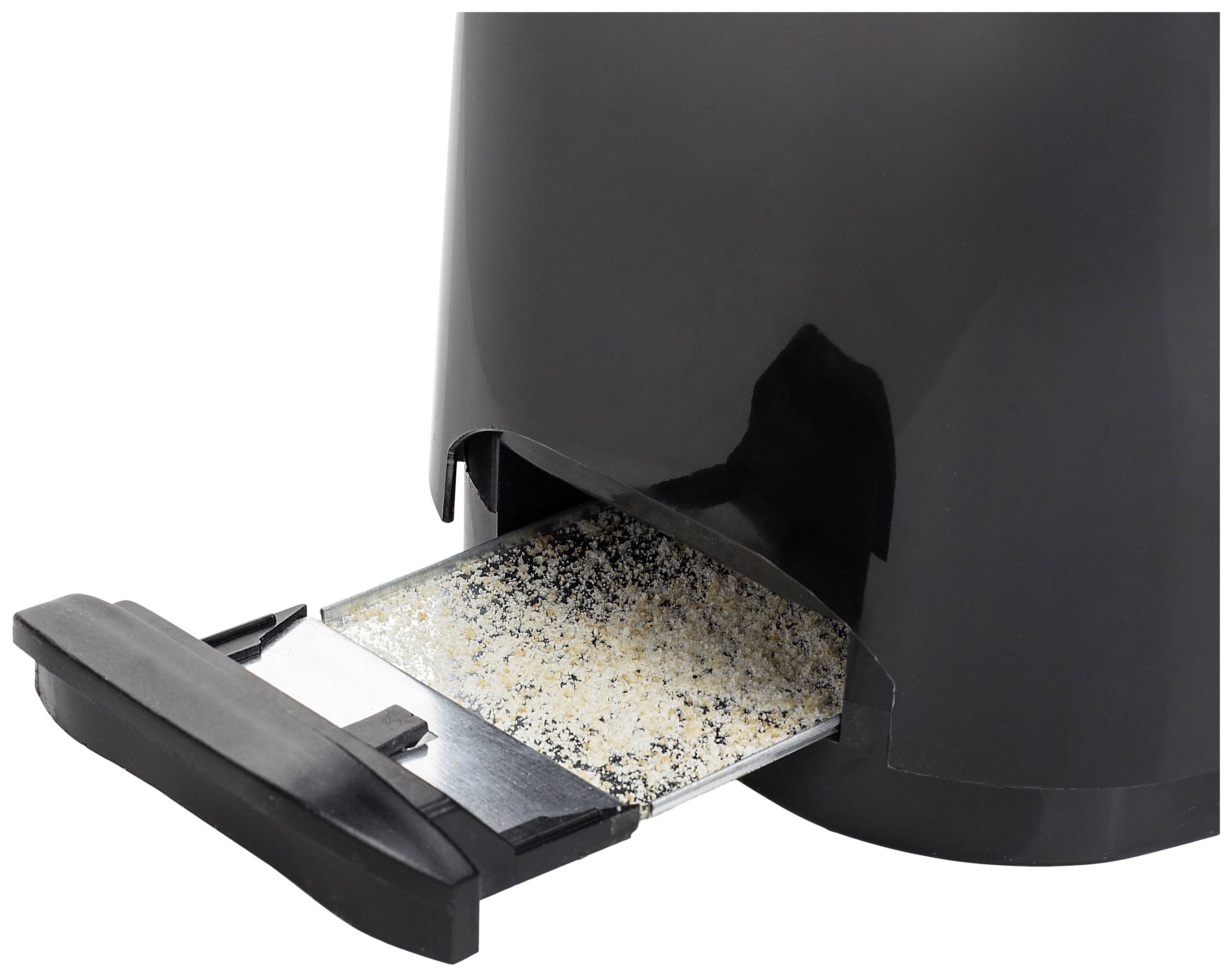 A black container with a removable base plate shows scattered granules on it.