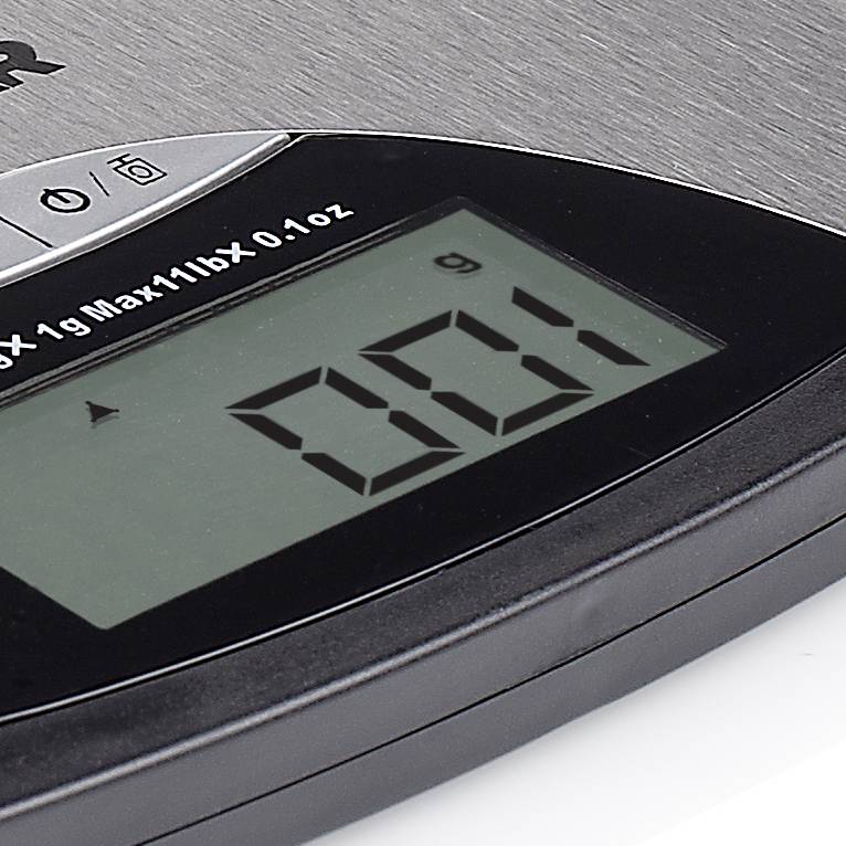 Close-up of a digital kitchen scale with a display showing '801 g' against a metallic background.