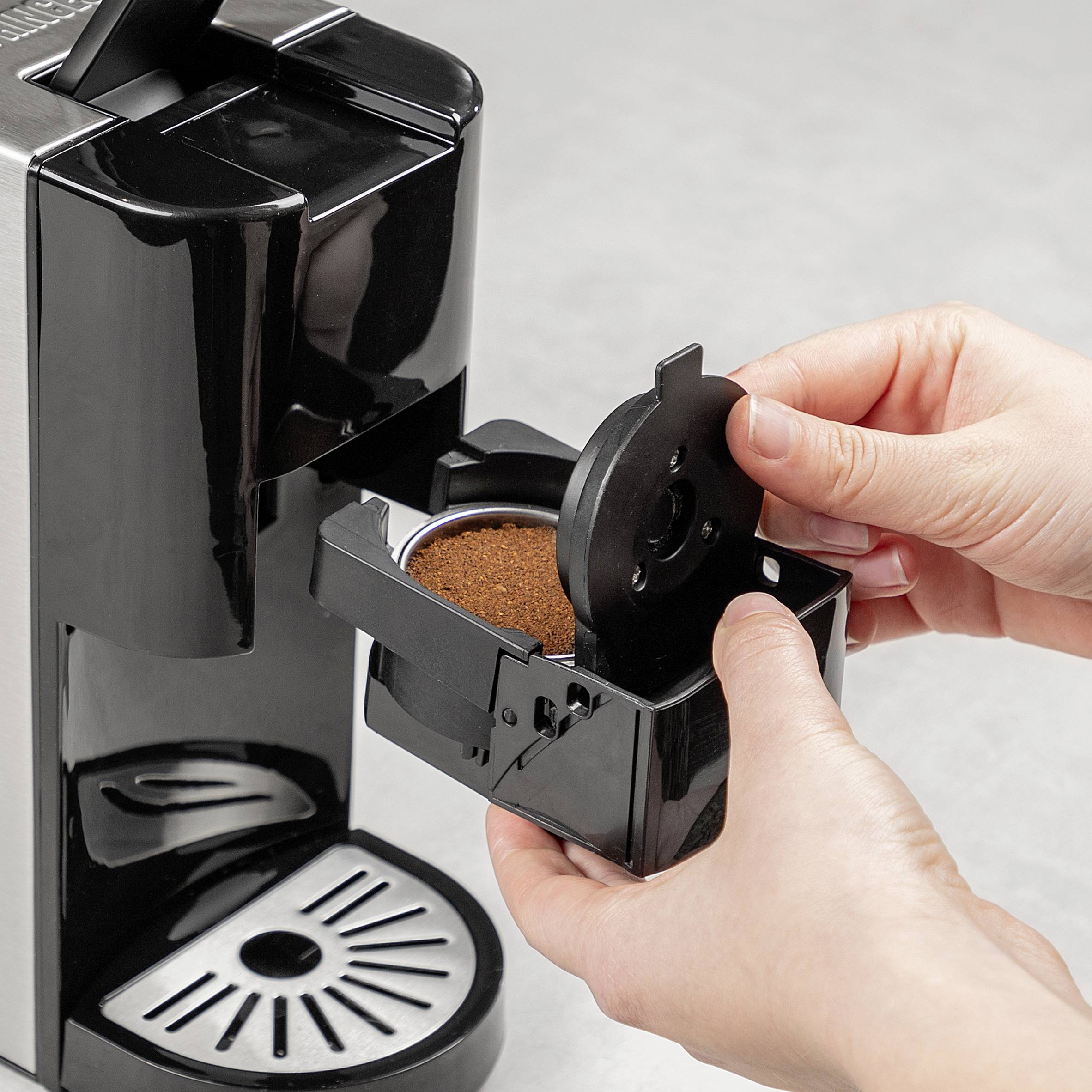A person is preparing the coffee machine by inserting the container with coffee grounds.
