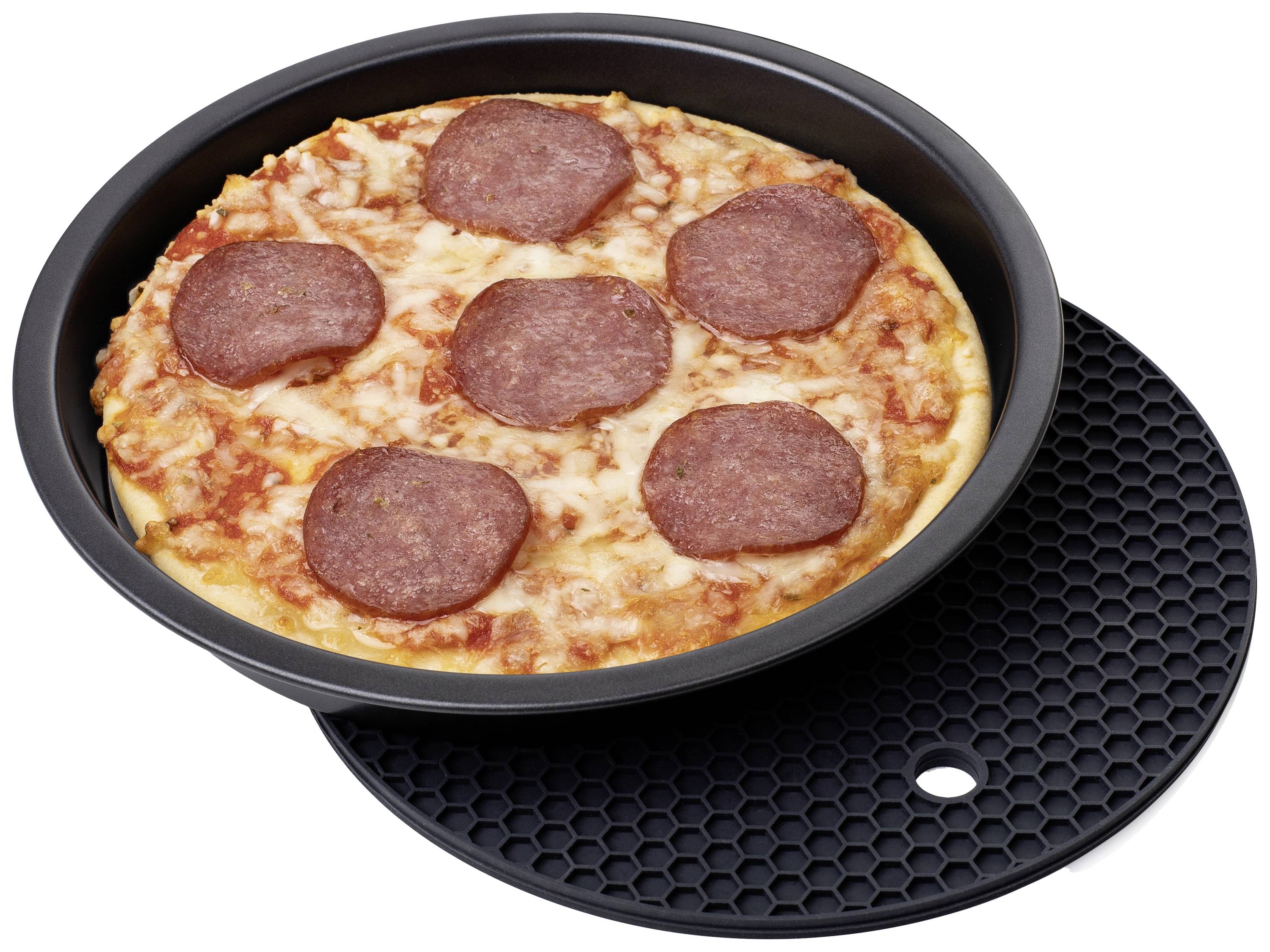 A pizza with salami is sitting in a black baking tray on a textured surface.