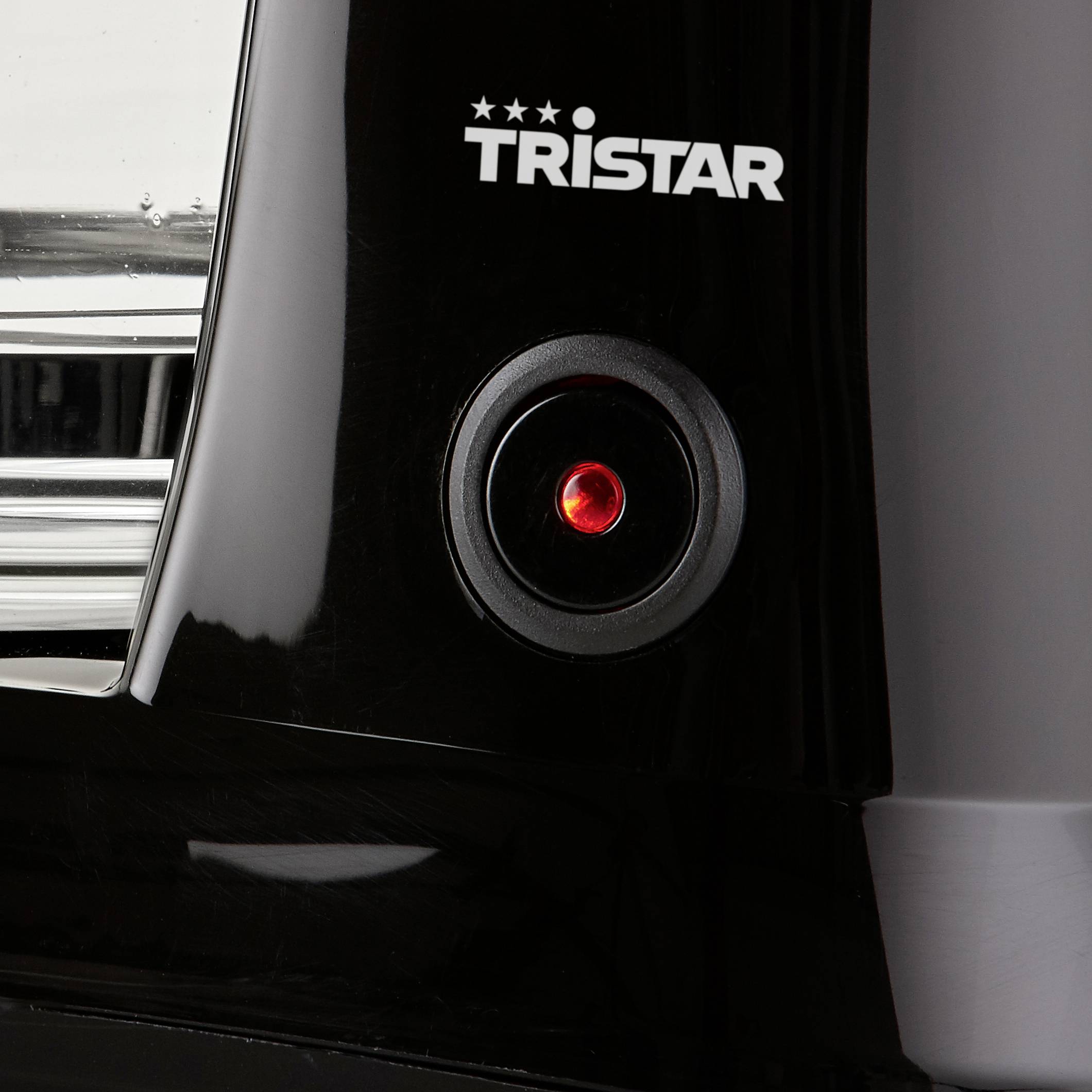 Close-up of a black device with a glowing red button and the inscription 'Tristar'.