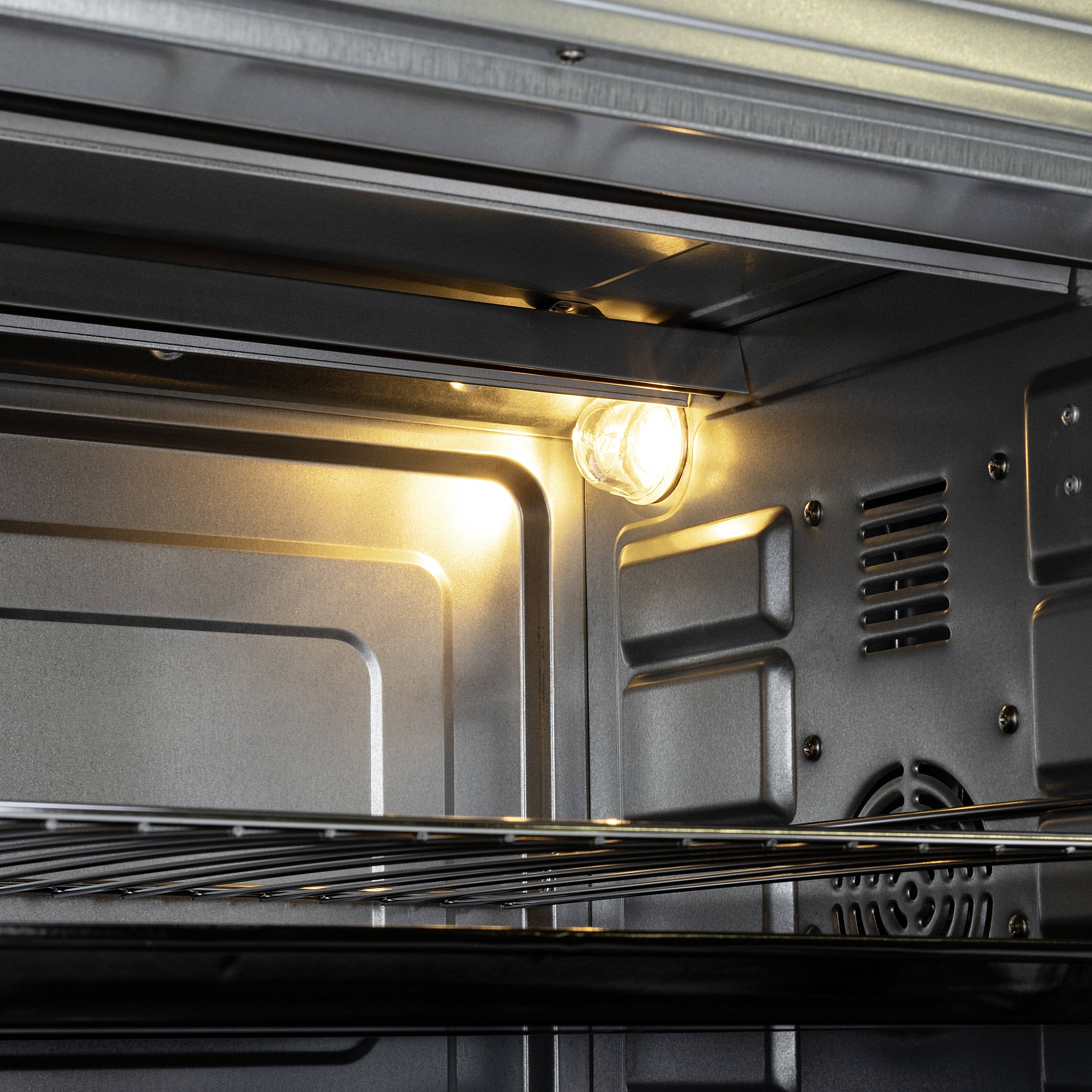 An open oven with the light switched on. Metal rack and interior walls are visible.