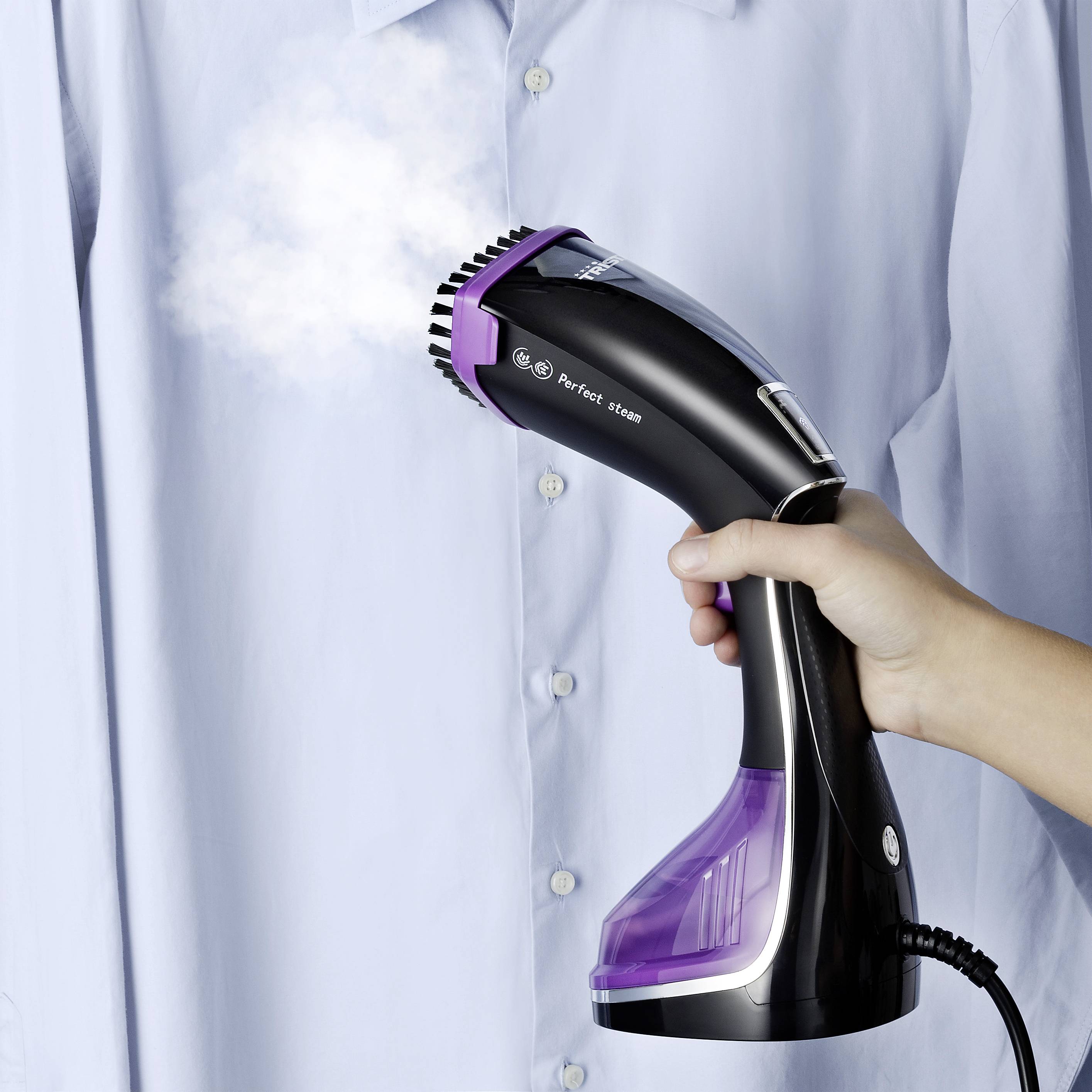A handheld steamer smooths out creases on a blue shirt. One hand is holding the device, from which steam is emerging.