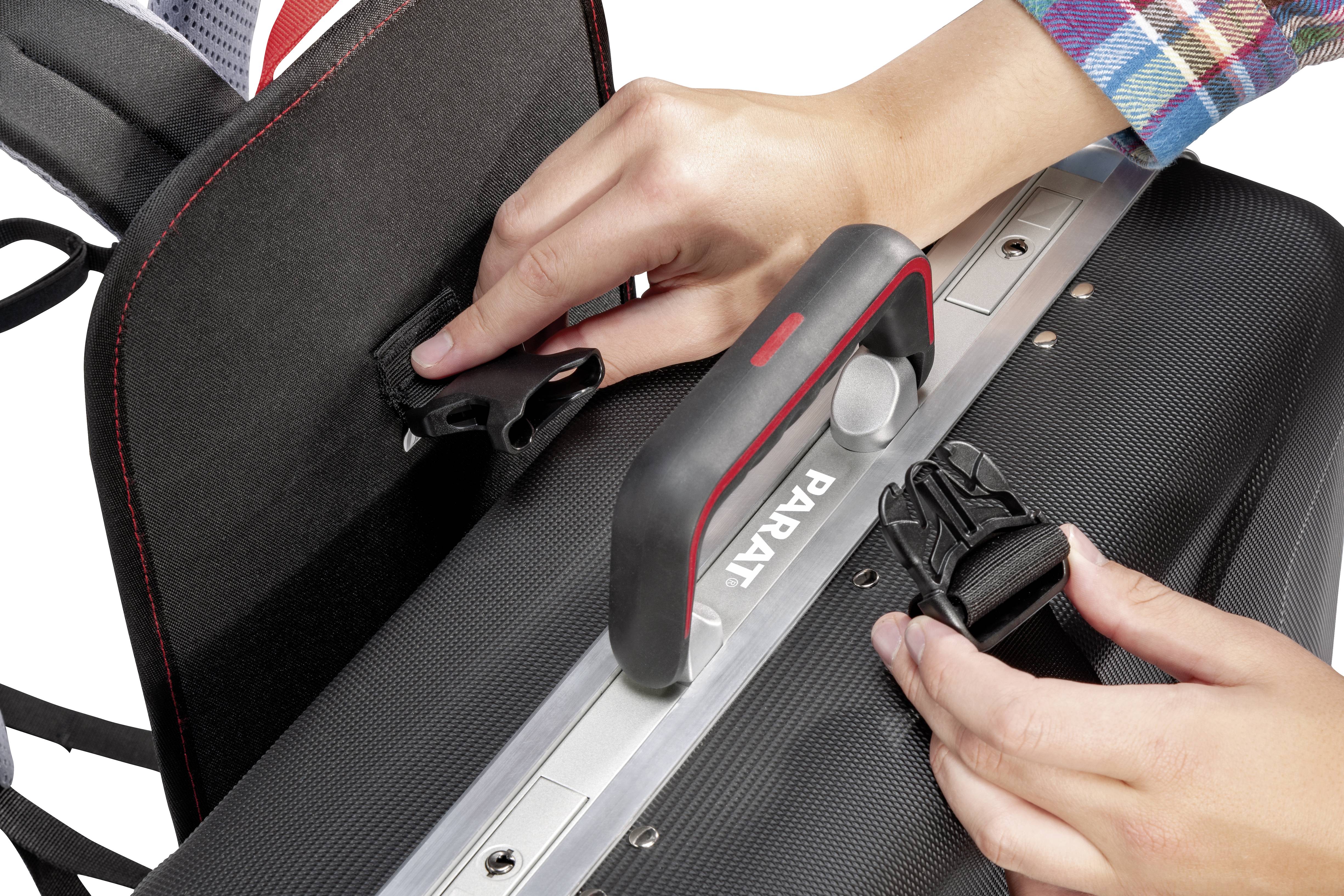 Hands secure backpack straps. One person adjusts the straps of a black rucksack with red and grey handles.