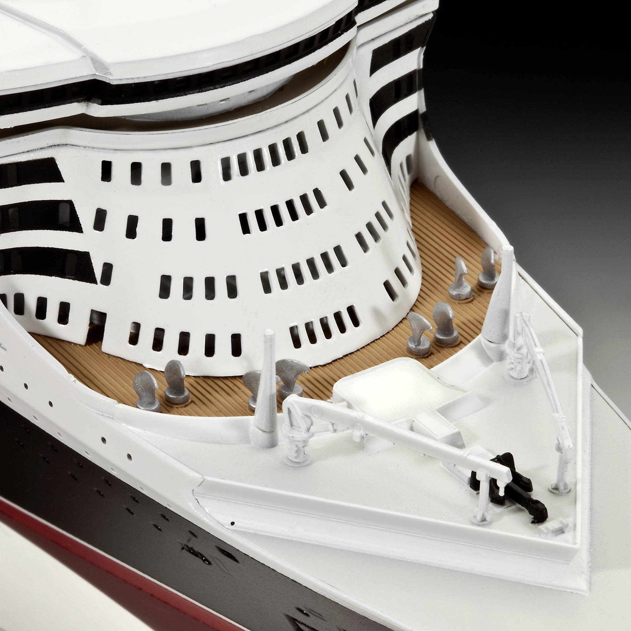 A detailed model of a ship with a white and black hull and light-coloured deck structures in close-up.