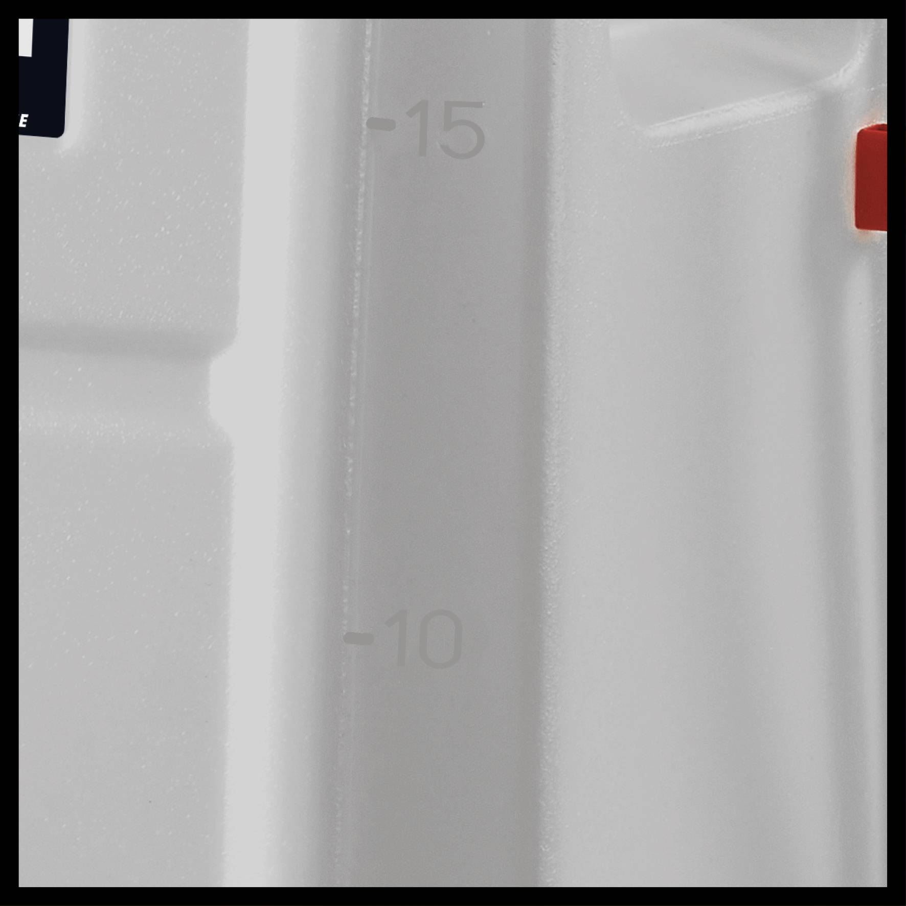 Close-up of a white container with a measuring scale from -15 to -10, rectangular in shape, with a smooth, glossy surface.
