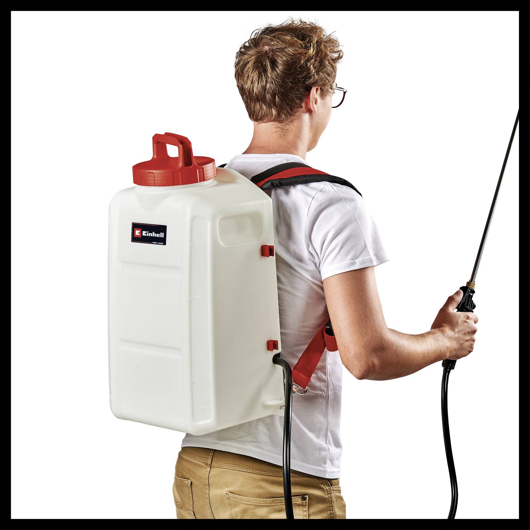 A man wearing a back-mounted sprayer and hose is spraying; he is wearing a white T-shirt and beige trousers.