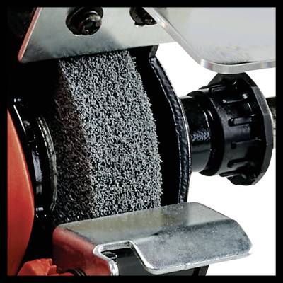 Industrial metal cutting machine with grinding wheel, close-up. Focus on structured metal wheel and protective cover.