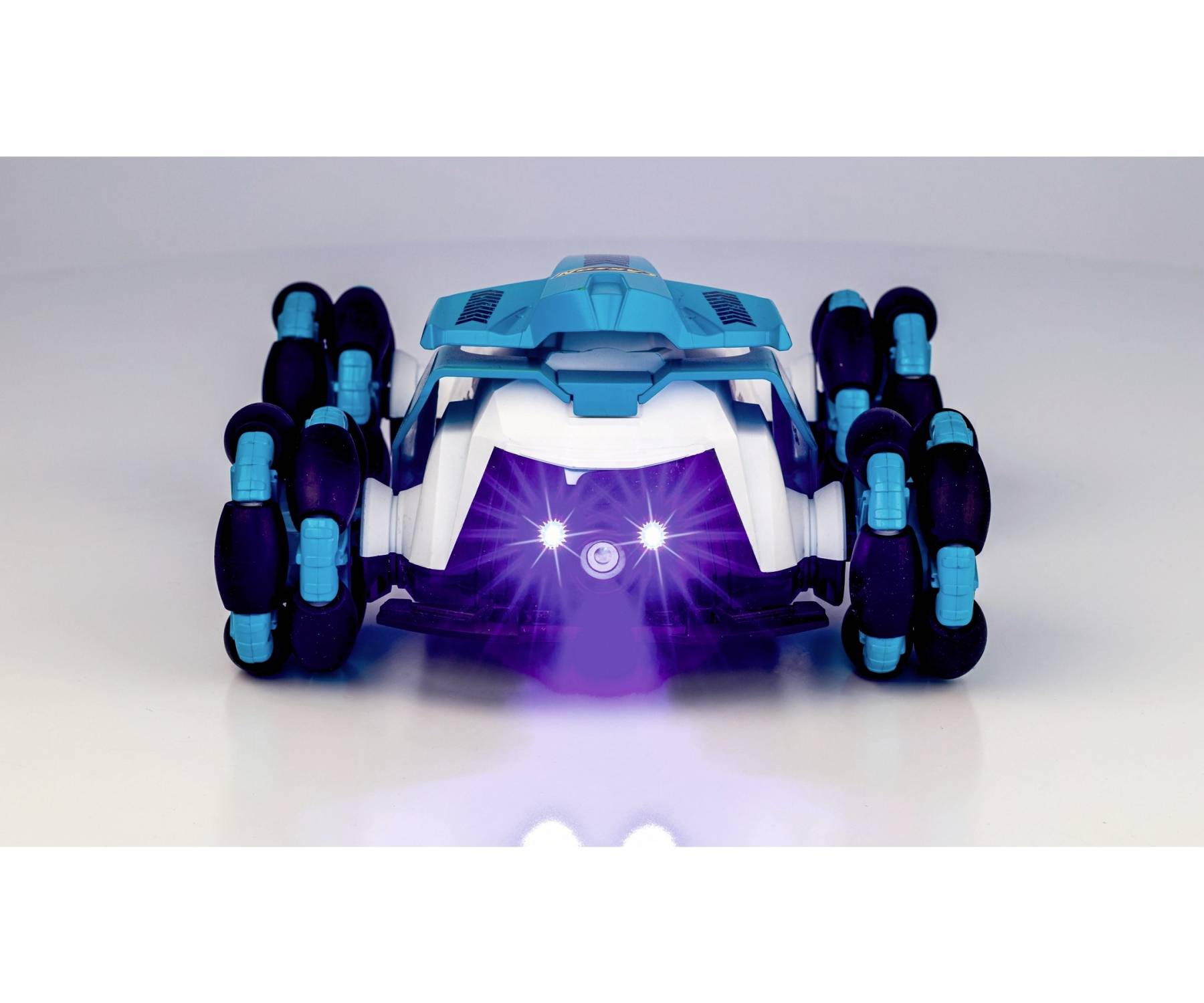Toy car with blue and black wheels driving on a smooth surface. Front lights shining brightly.