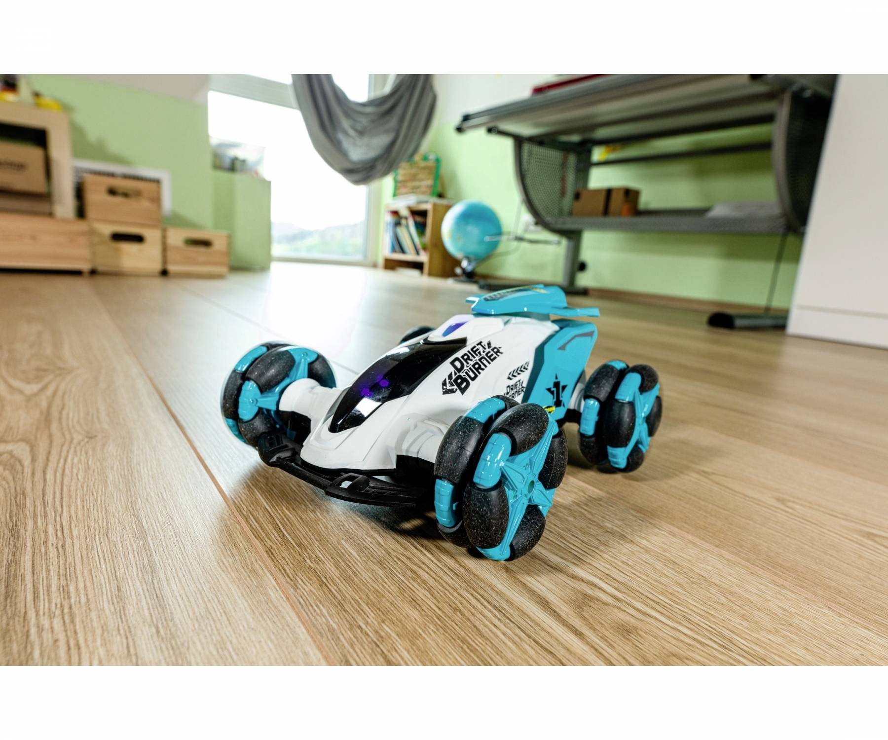 Toy car with blue and black wheels on a wooden floor in a room with green walls and a globe in the background.