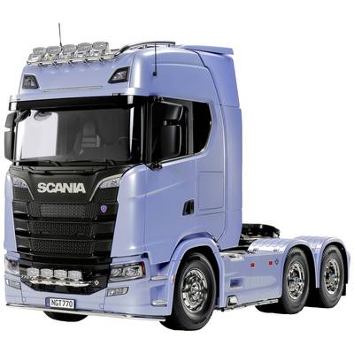A blue lorry with a large, modern cab and six wheels is standing on a white surface.