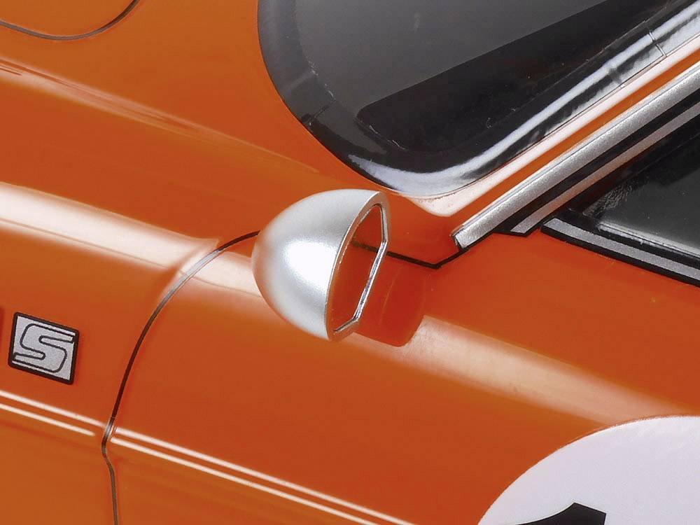 Close-up of an orange vintage car. A section of the driver's door is visible with a silver wing mirror.