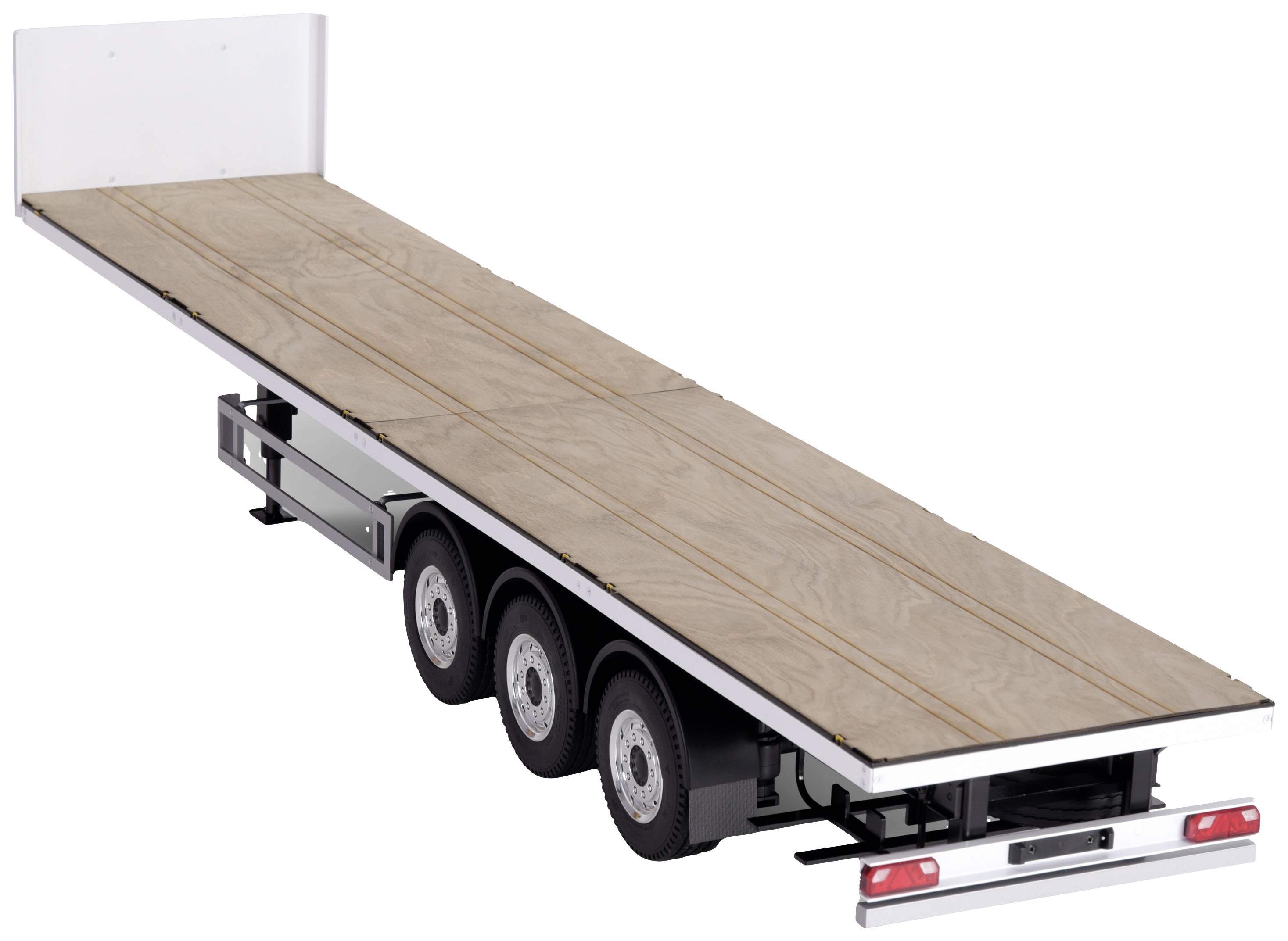 A long, flat trailer with three axles and a wooden platform, without side boundaries, is used for transporting large or bulky items.