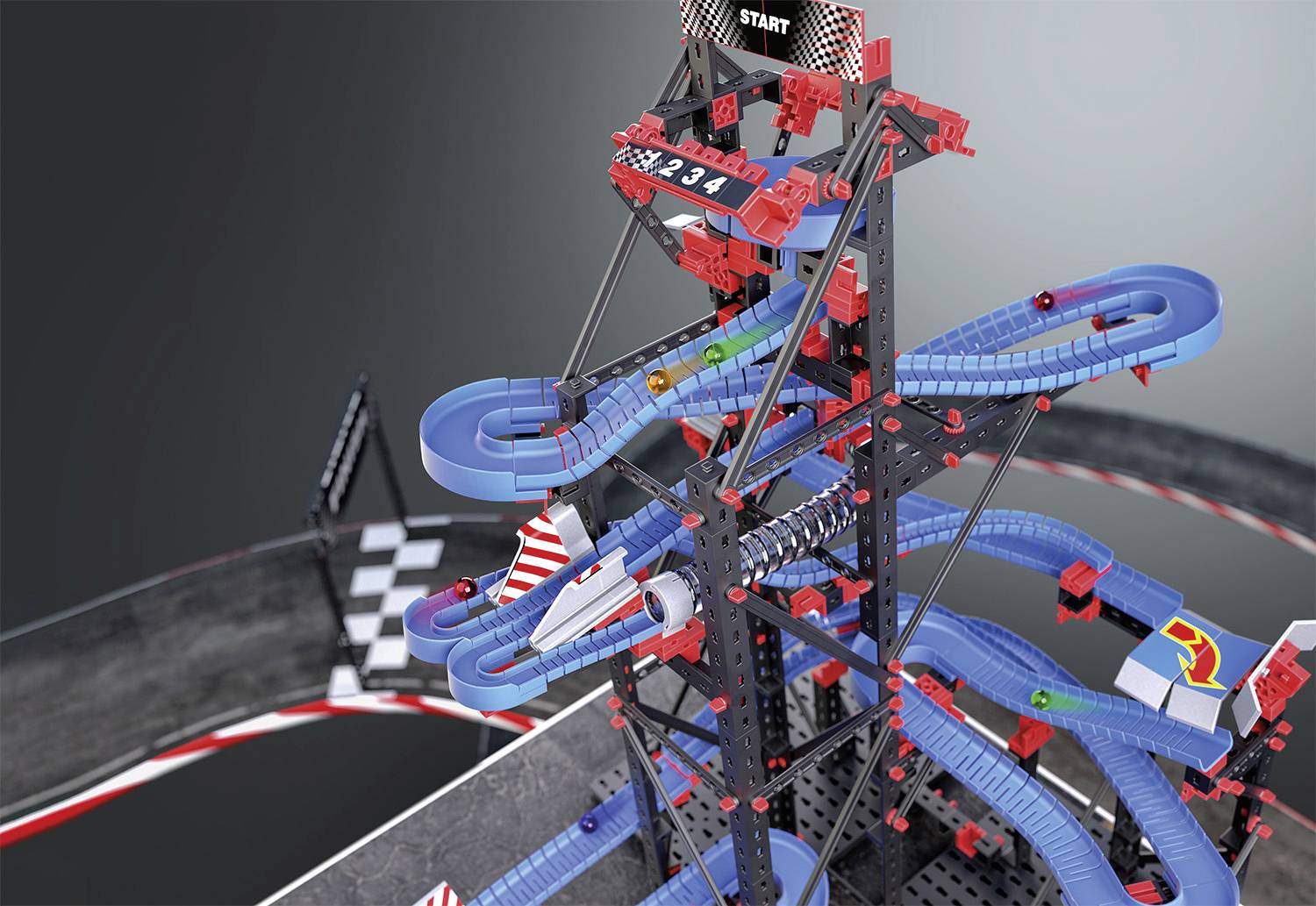 A marble run tower made of blue and red modular parts, where marbles travel along winding tracks, with a starting line at the top.
